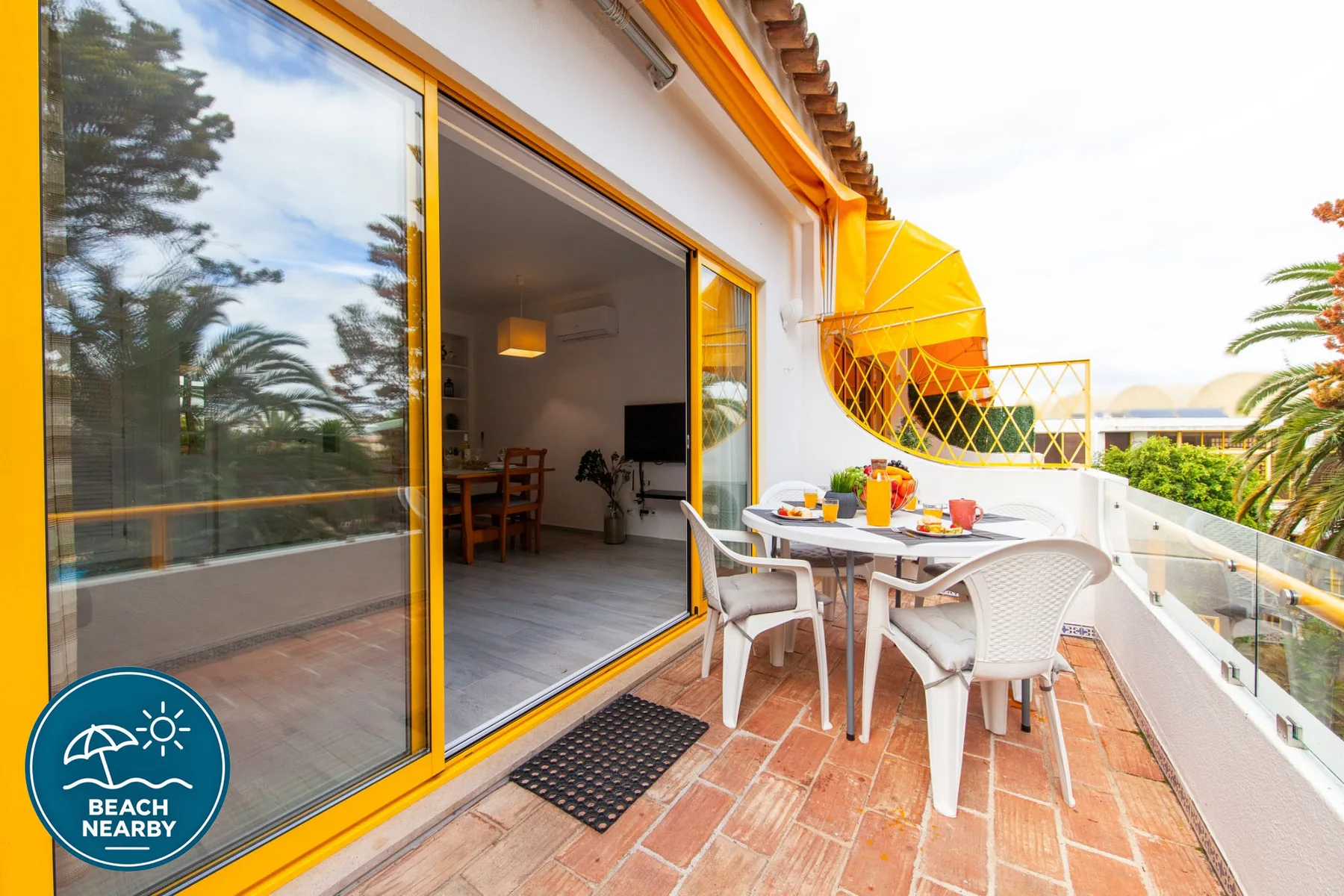 A tiled balcony has an outdoor dining table beside a large sliding glass door.