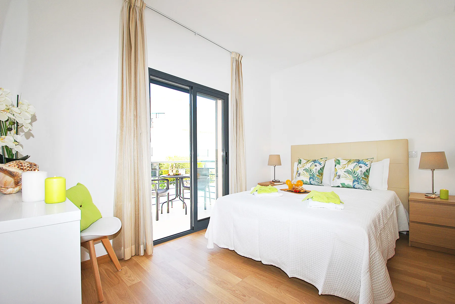 Dormitorio luminoso con una cama bien hecha junto a una puerta de cristal al balcón.
