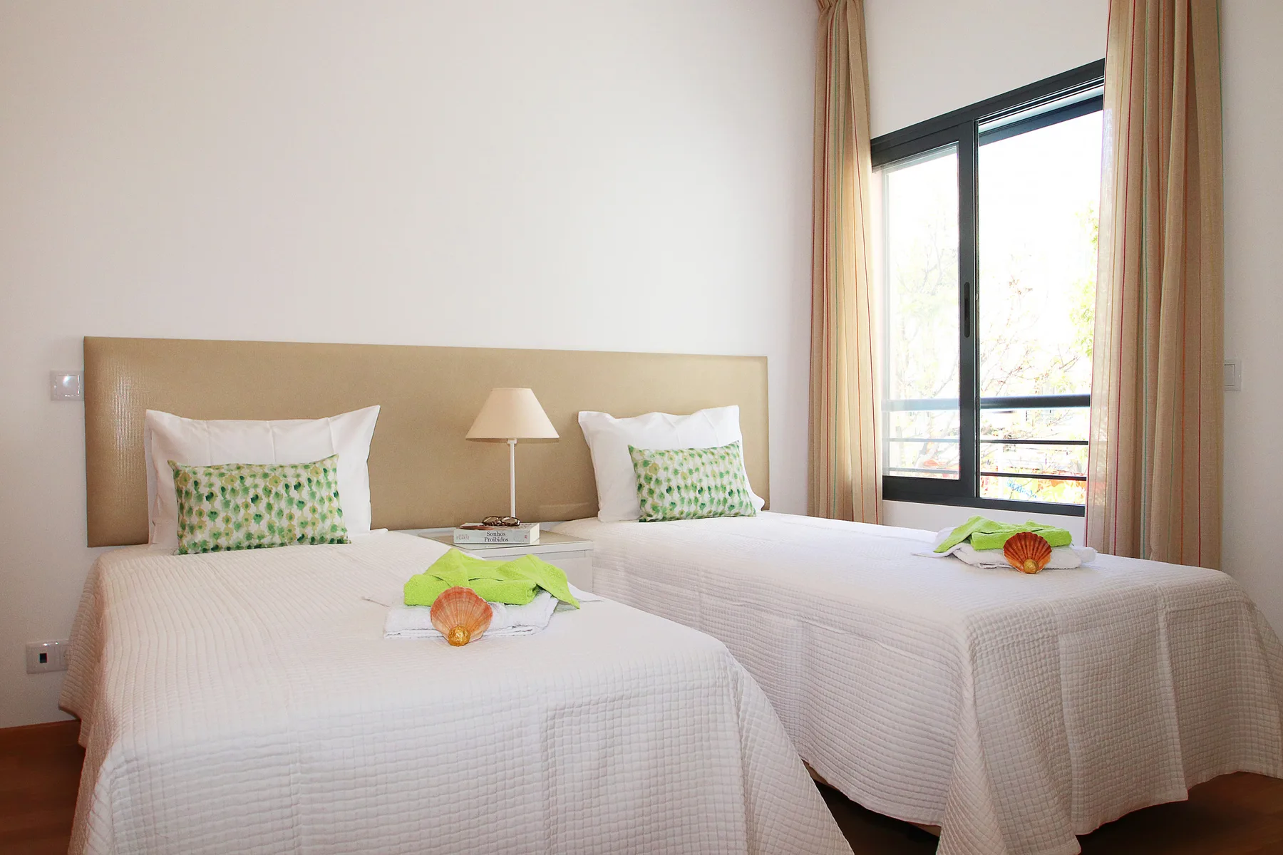 Un dormitorio luminoso con dos camas individuales y una ventana con cortinas.