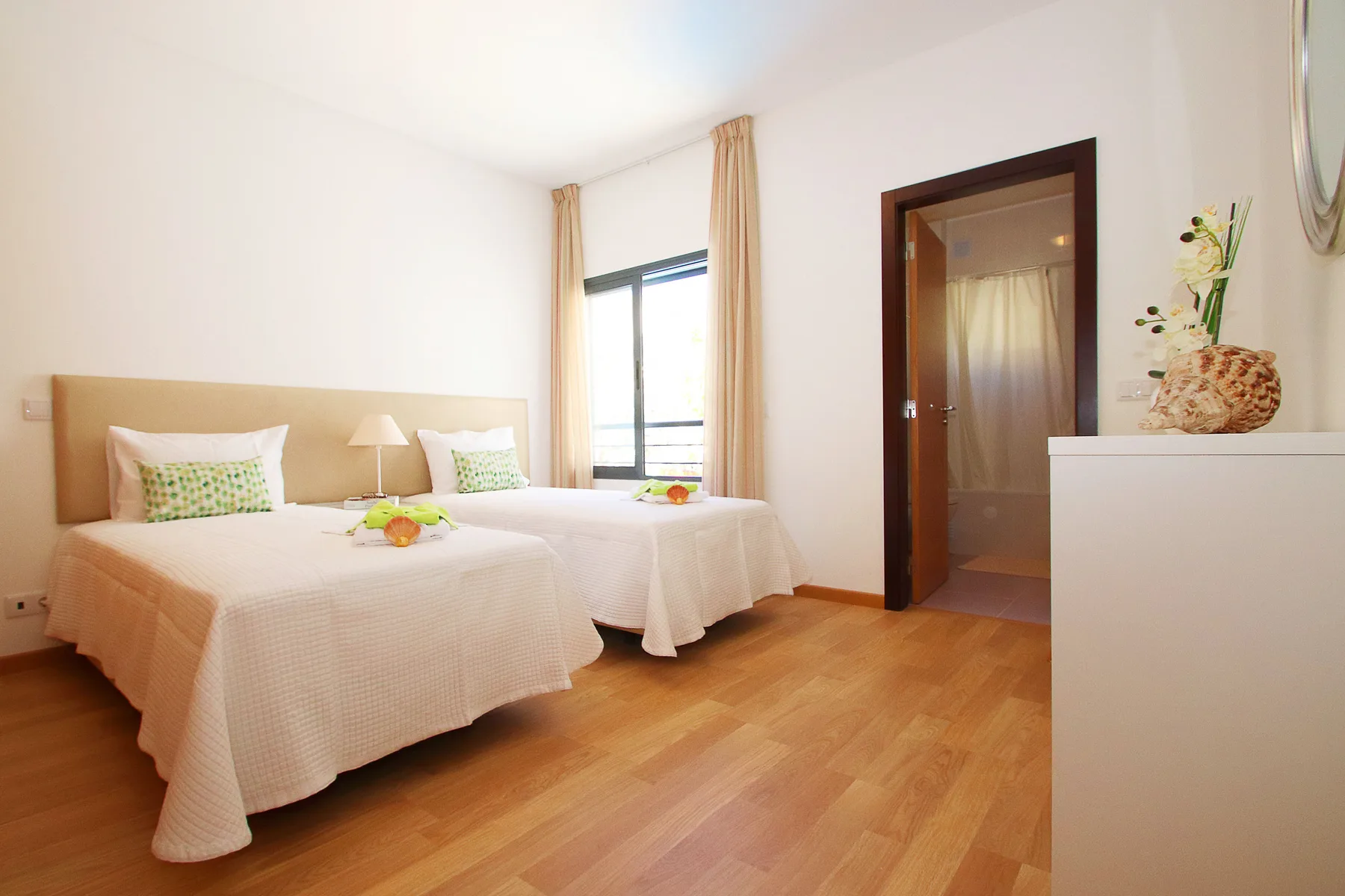 Un dormitorio luminoso con dos camas y una ventana.
