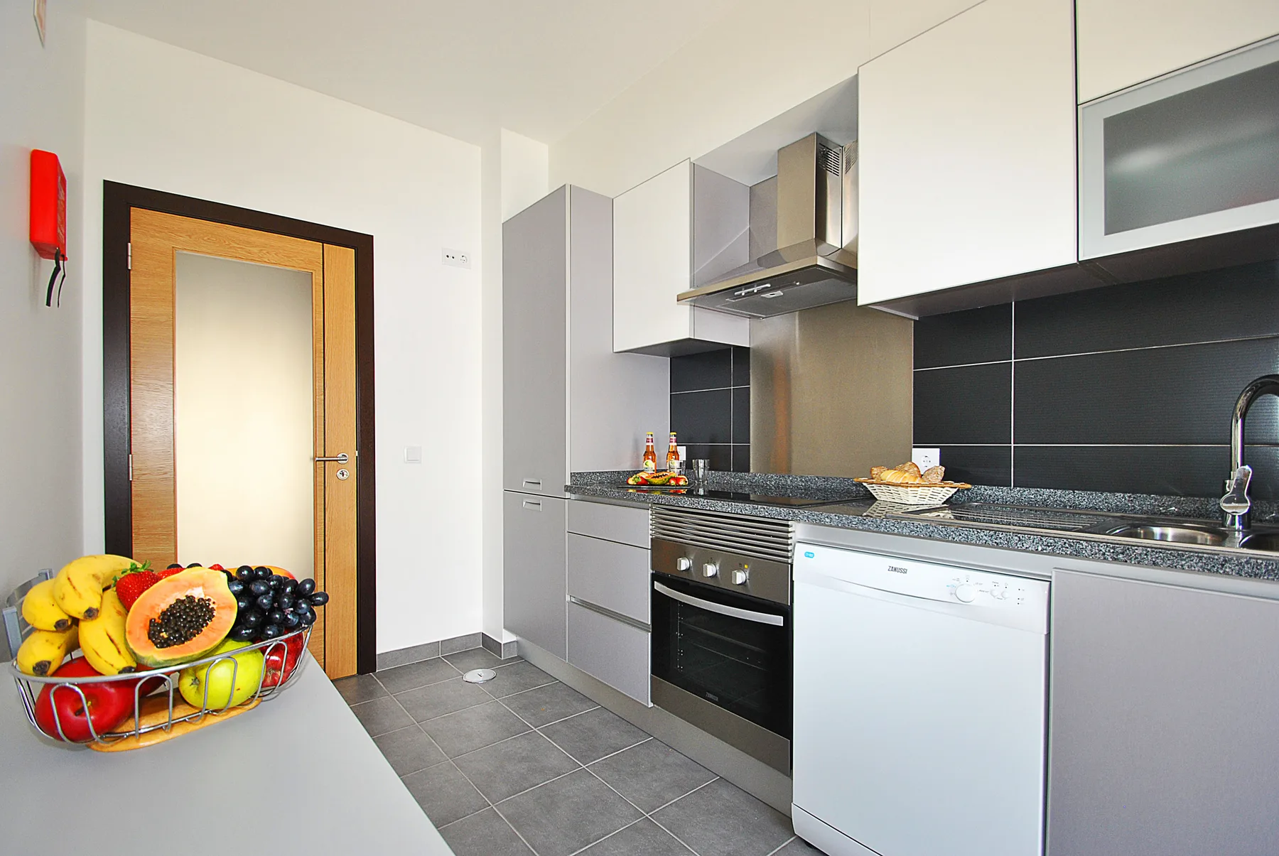Una cocina moderna con gabinetes grises, una encimera y un lavavajillas.