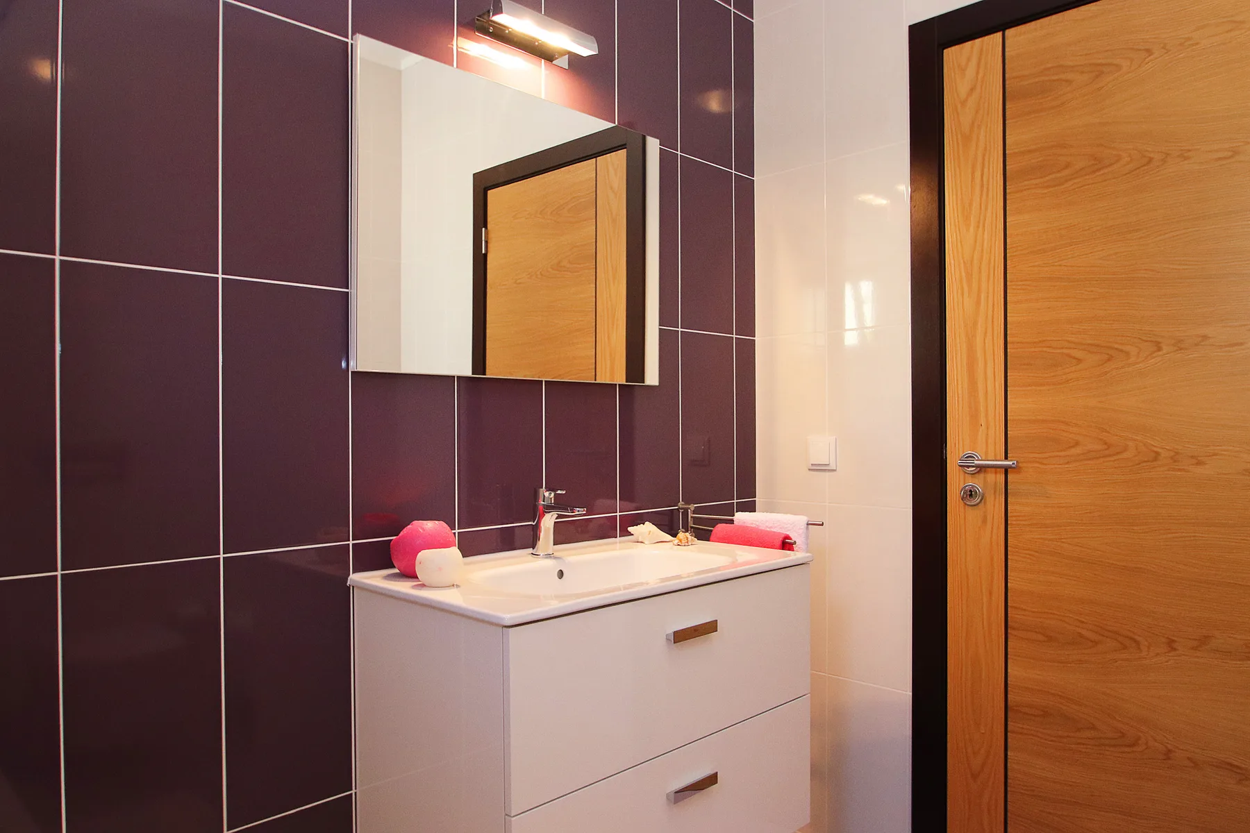 Un lavabo de baño con espejo está junto a una puerta de madera.