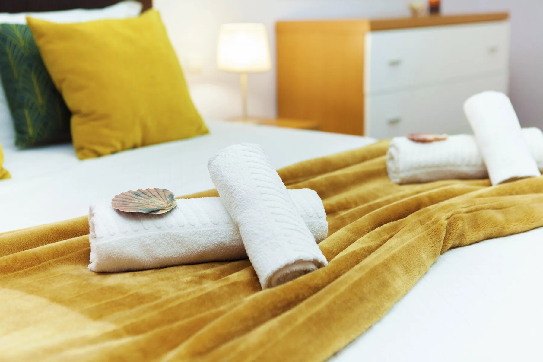 A bedroom with folded towels arranged on a mustard-colored bedspread.