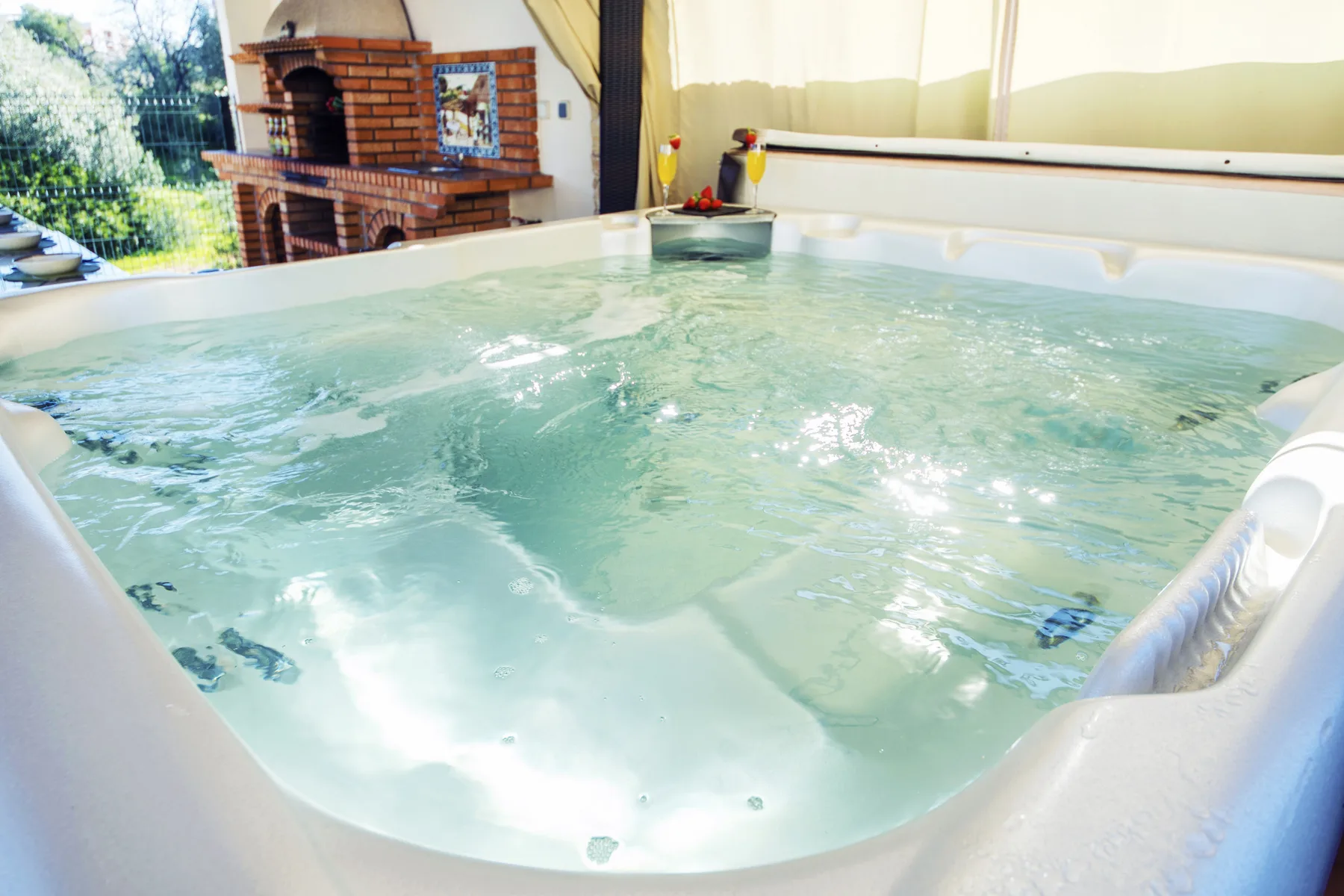 A bubbling indoor hot tub sits beside a brick fireplace.