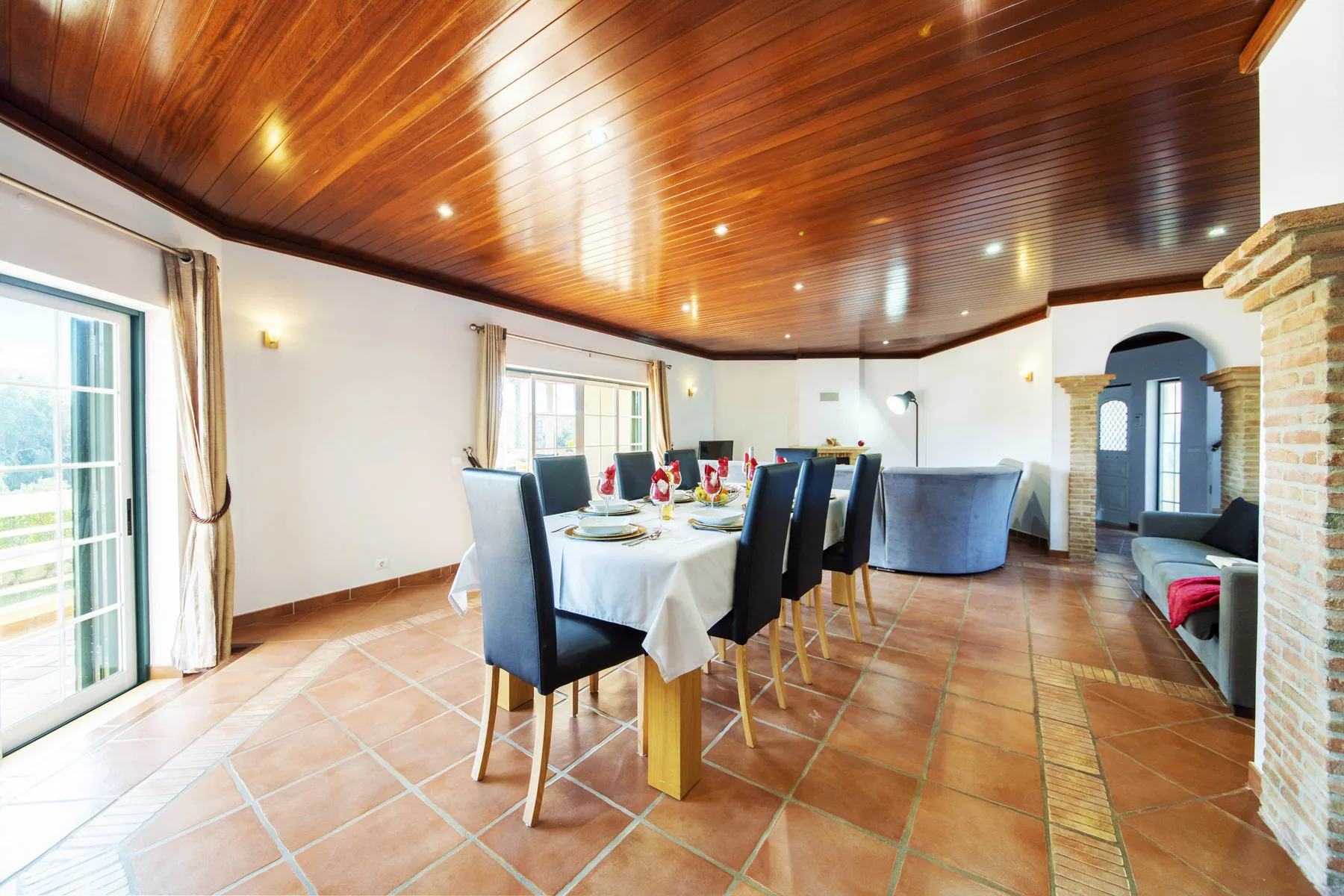 A dining area with a table and chairs beneath a wooden ceiling.