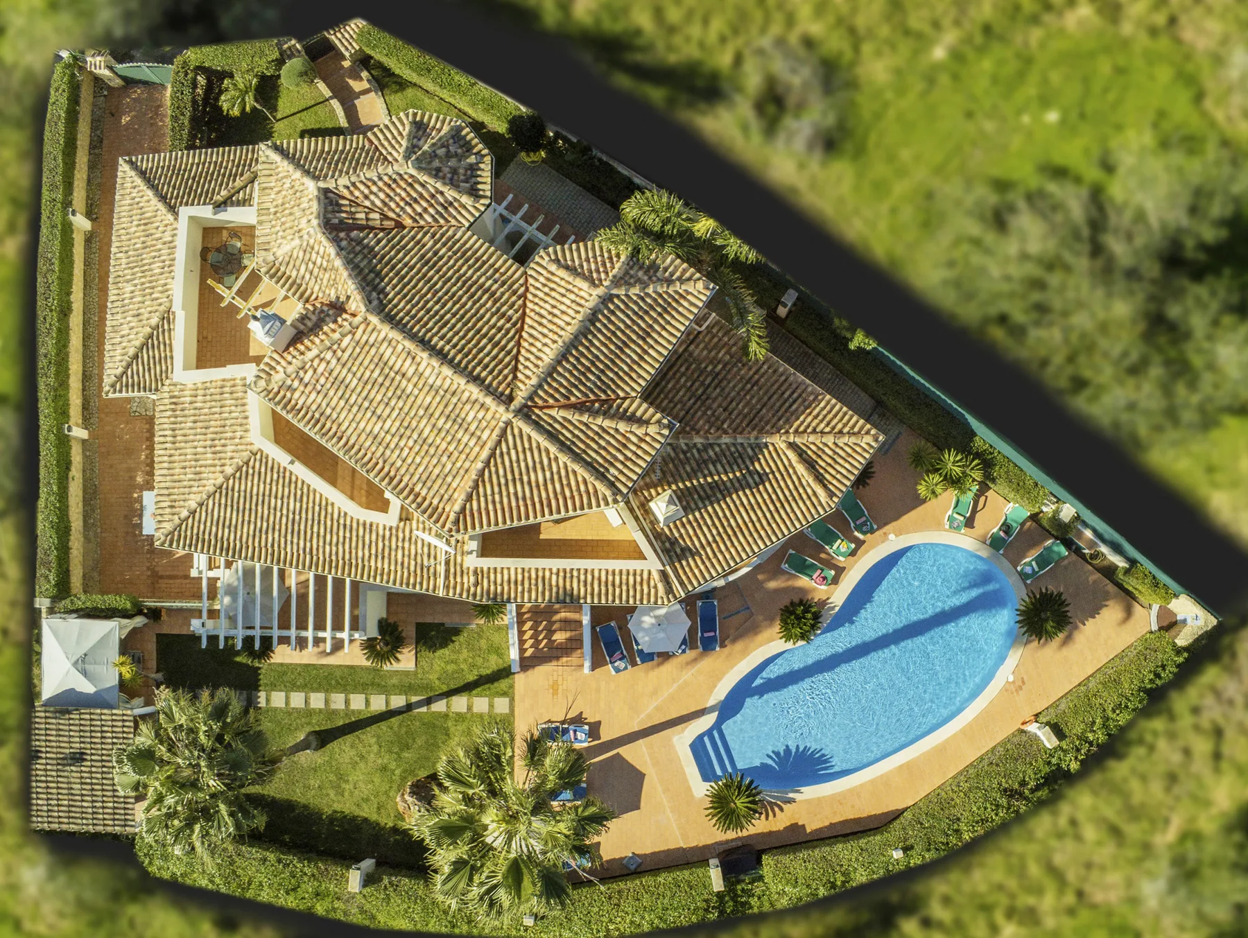 Aerial view of a tiled-roof house and a blue swimming pool.