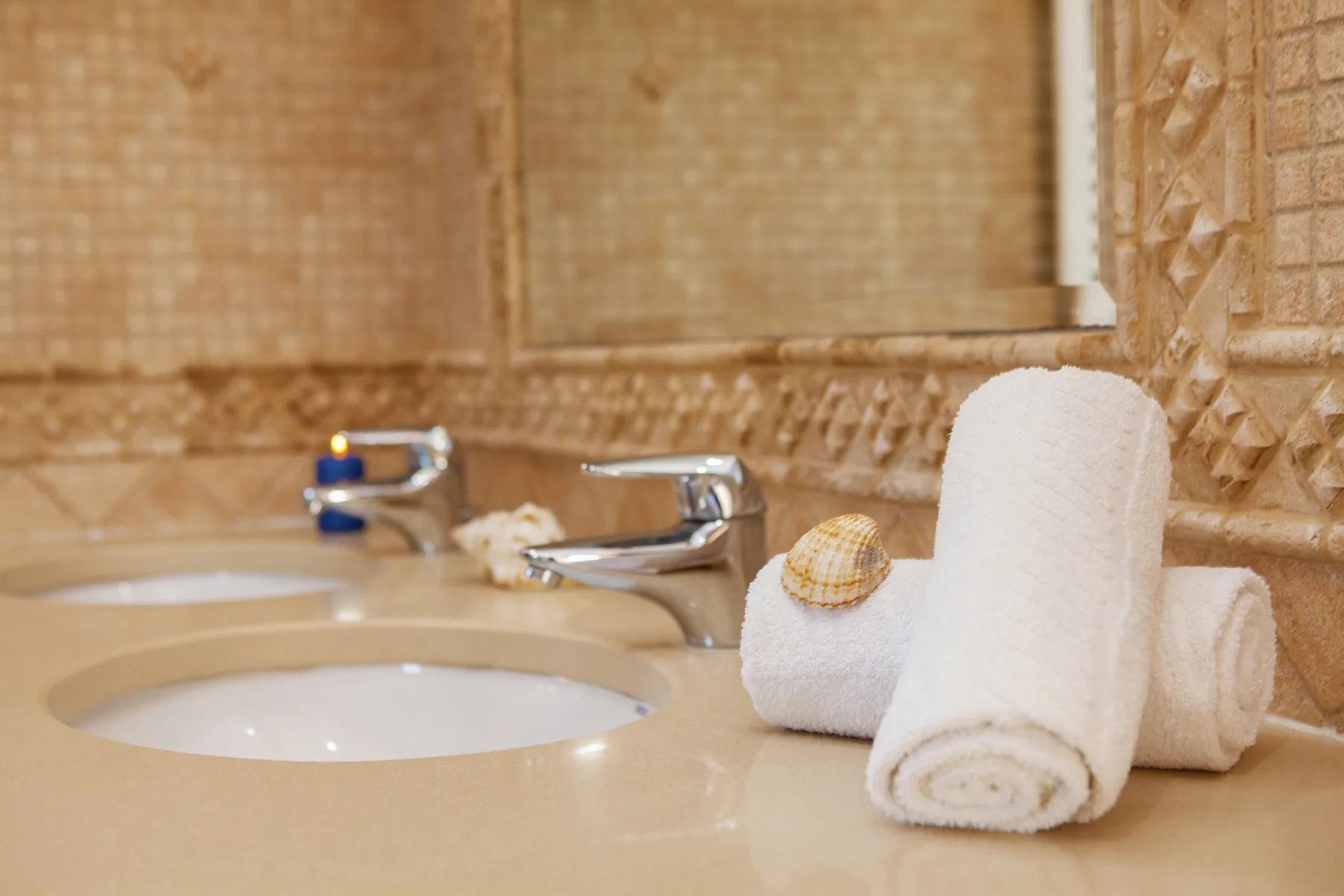 A bathroom vanity with a sink, faucet, and neatly rolled white towels.