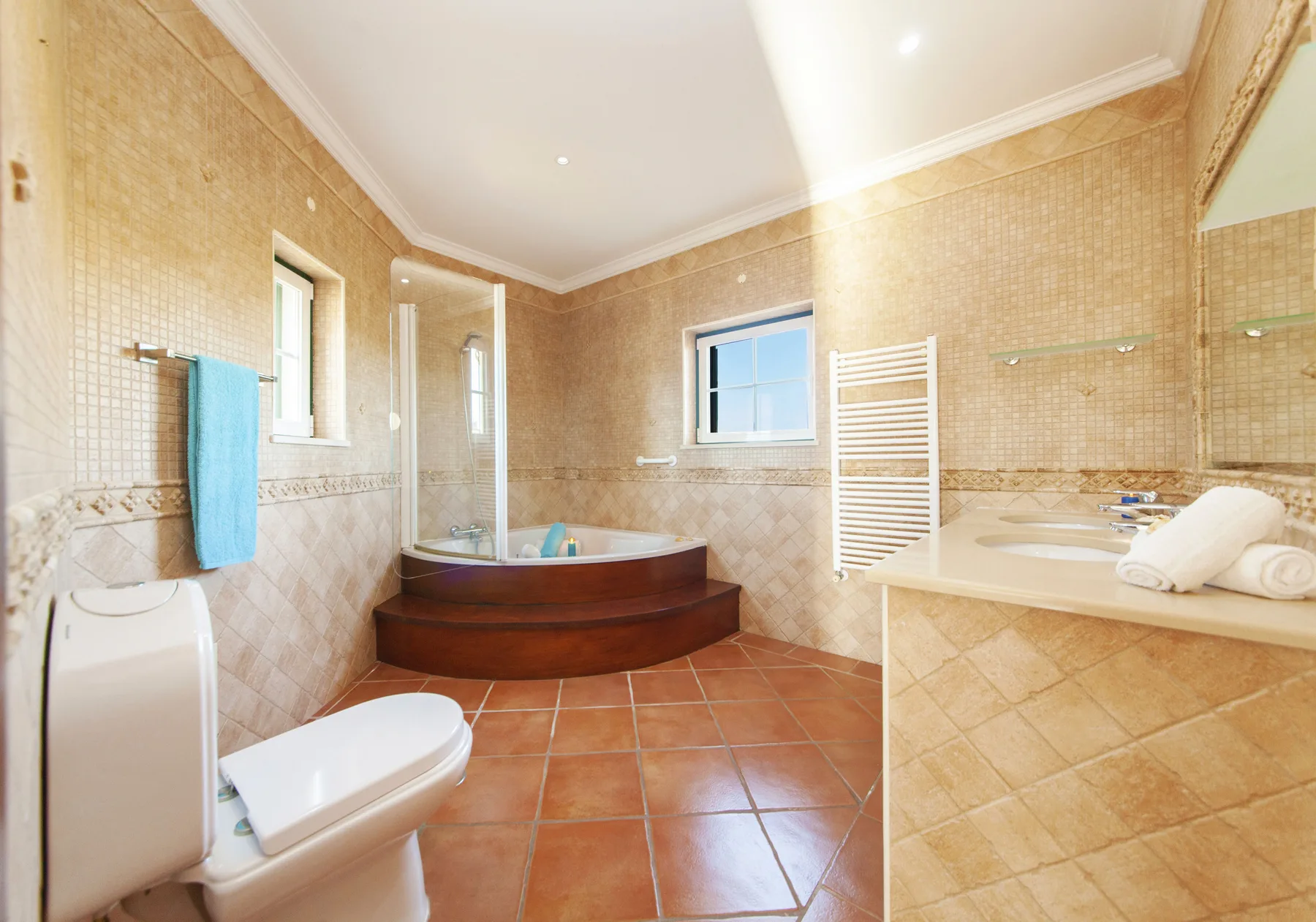 A tiled bathroom with a corner bathtub, toilet, and vanity.