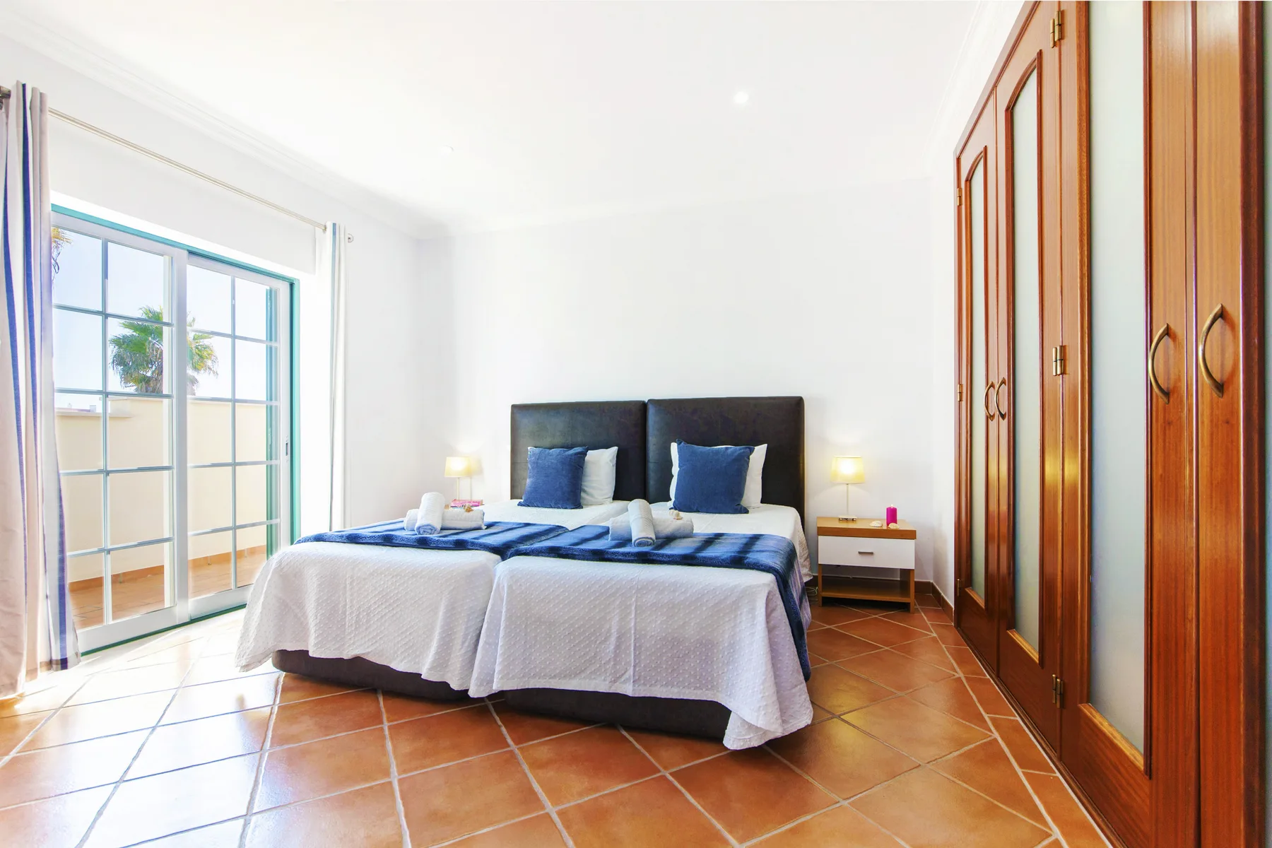 A bedroom with two beds beside a large glass door.