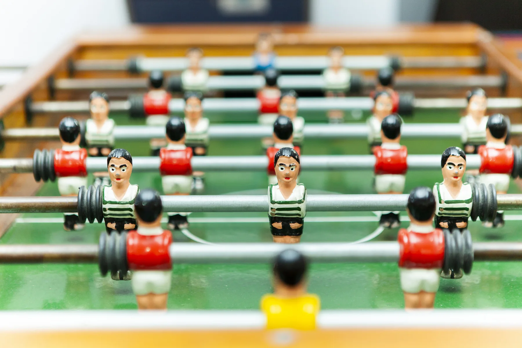 A tabletop foosball game with miniature players arranged across a green field.