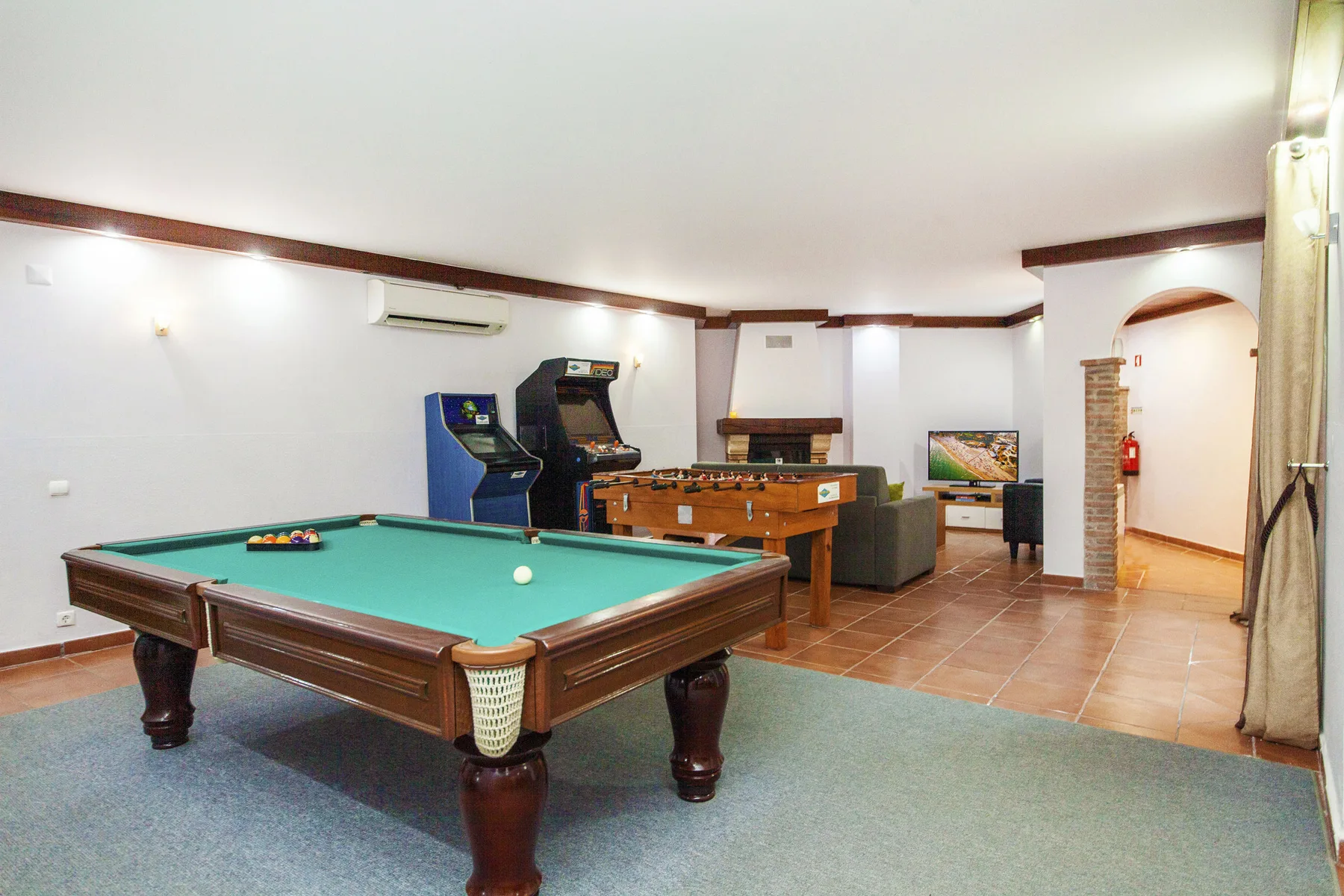 A recreation room with a pool table, arcade games, and a foosball table.