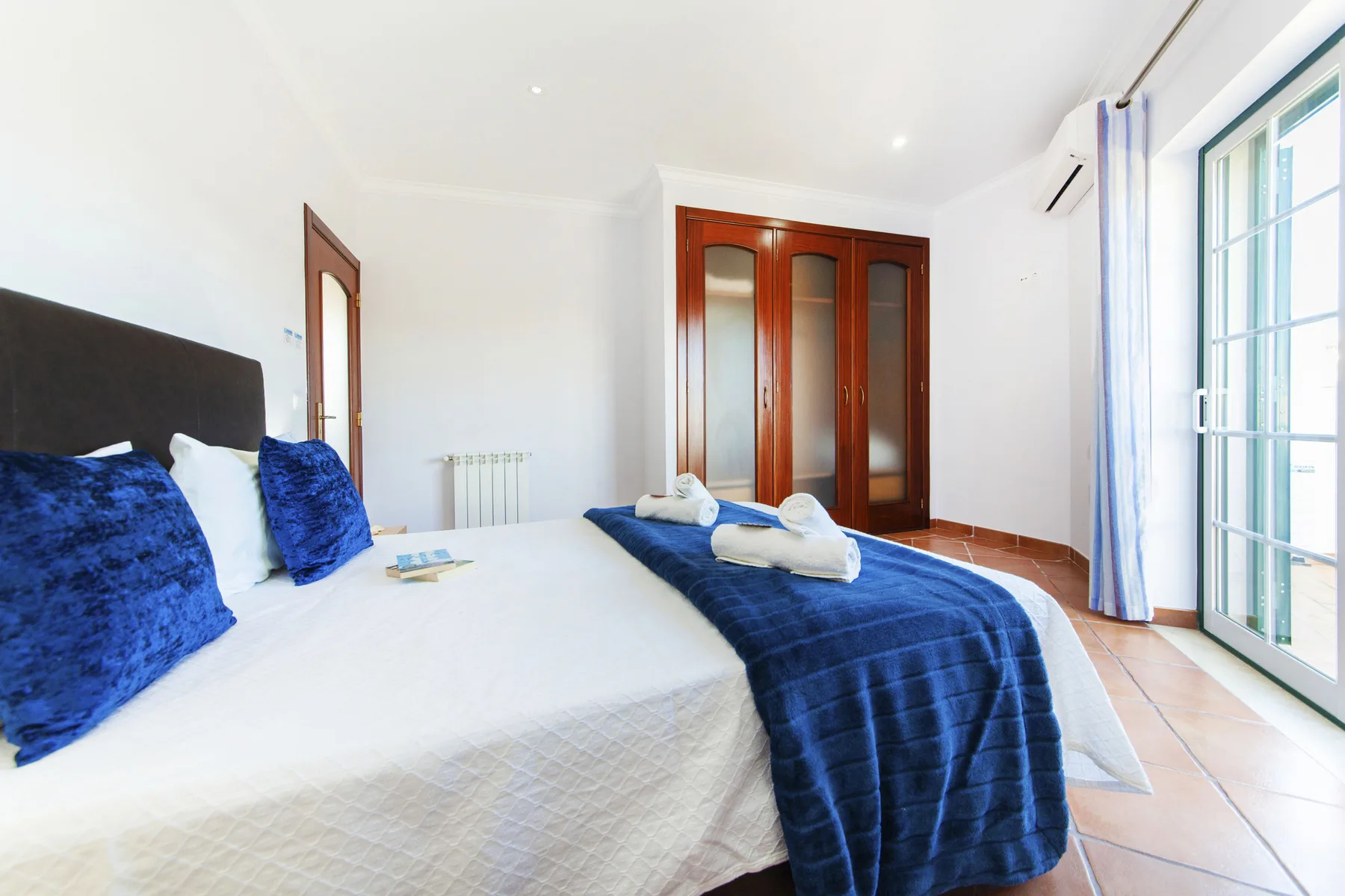 A bright bedroom with beds dressed in white and blue linens.