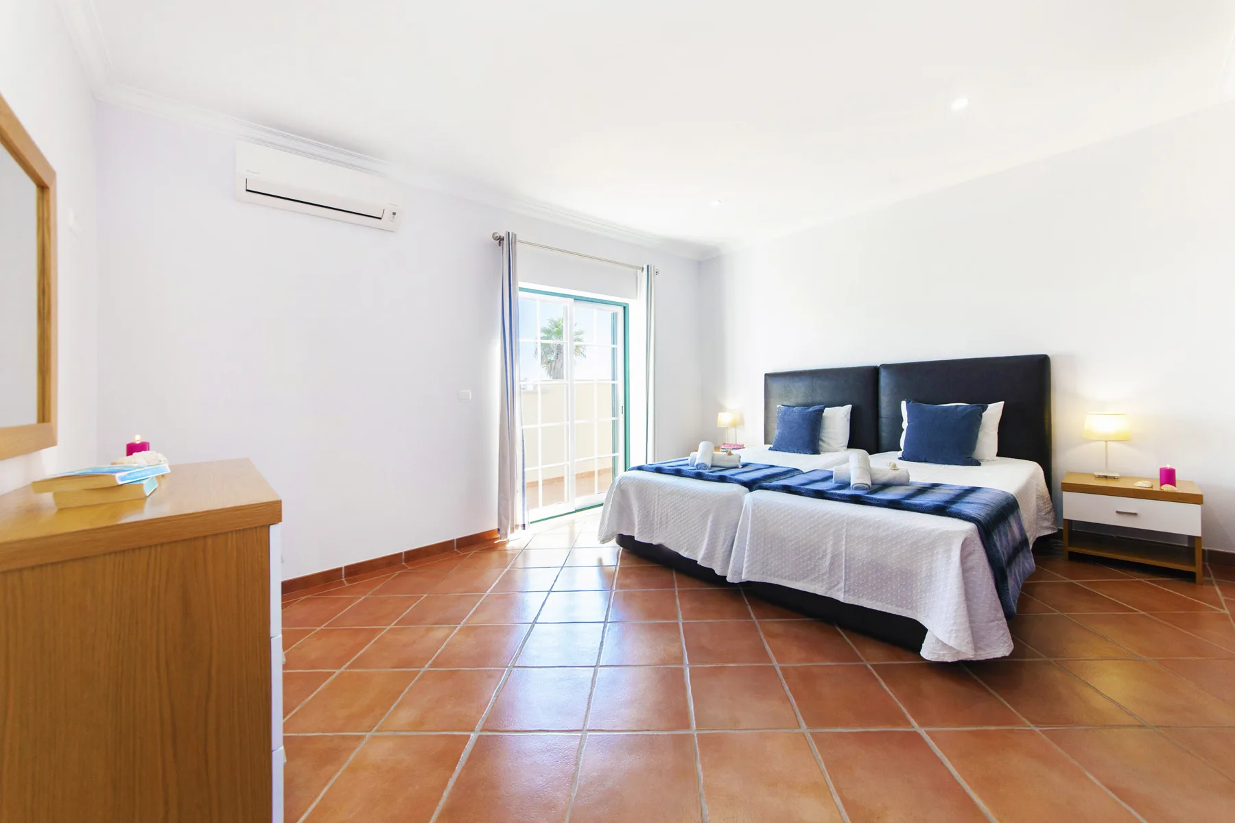 A bright bedroom with a large bed beside a glass door.