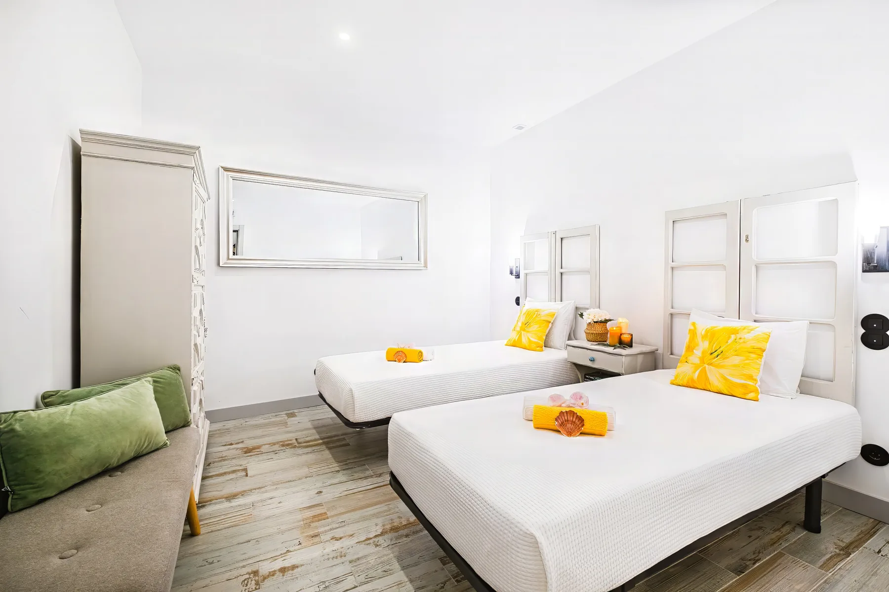 A bright bedroom with two beds and a small sofa.