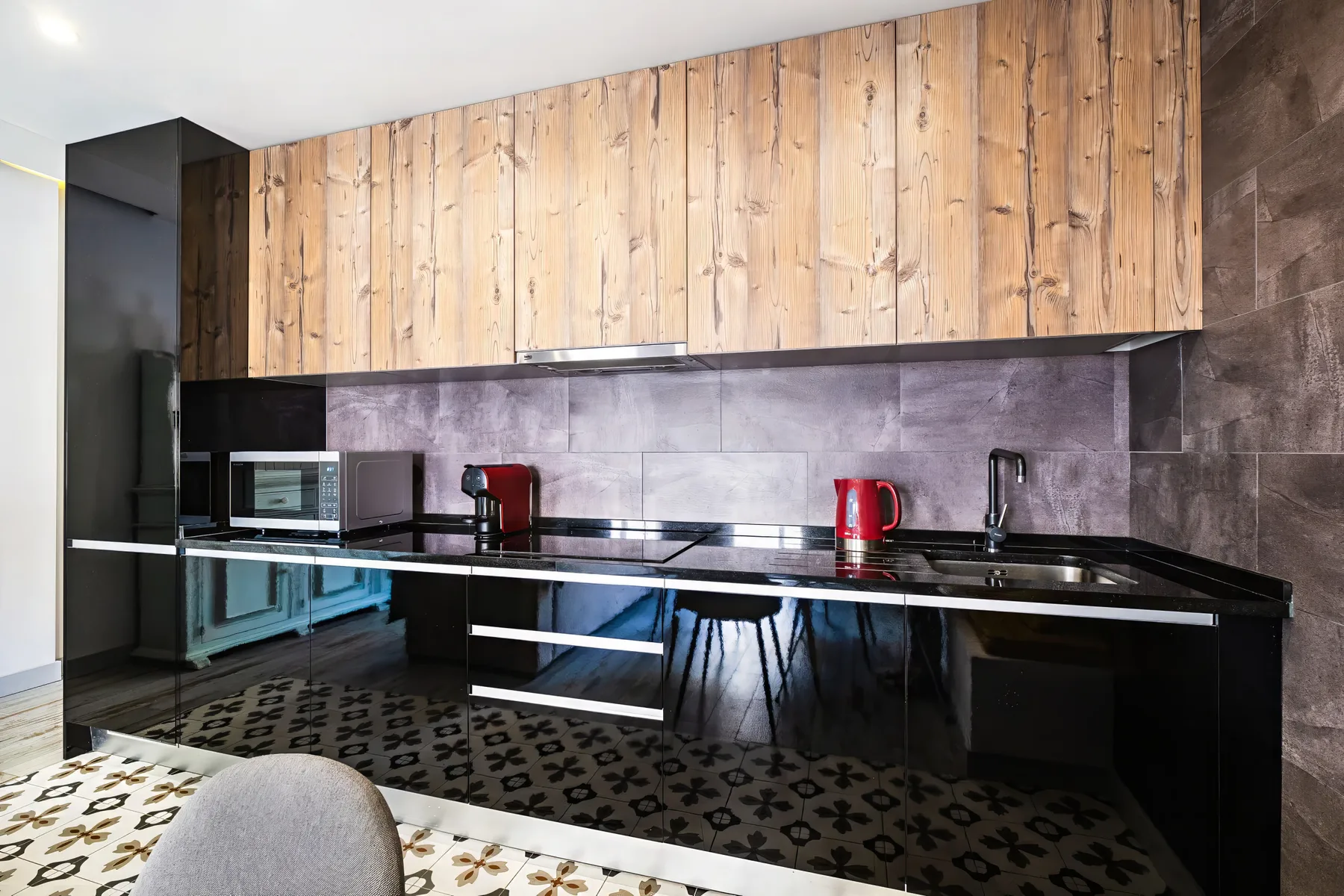 A modern kitchen with wood-front cabinets, a dark counter, and small appliances.