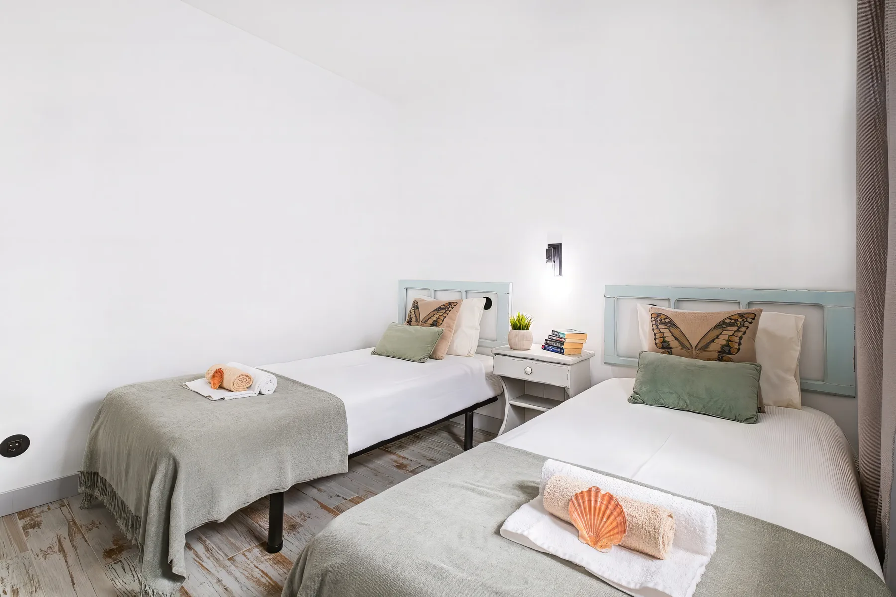 A bright bedroom with two beds and a small table between them.