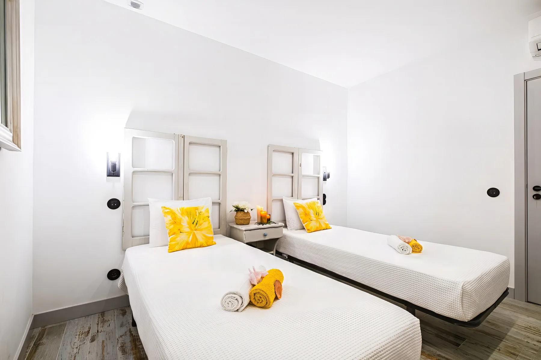 A bright bedroom with two single beds and folded towels.