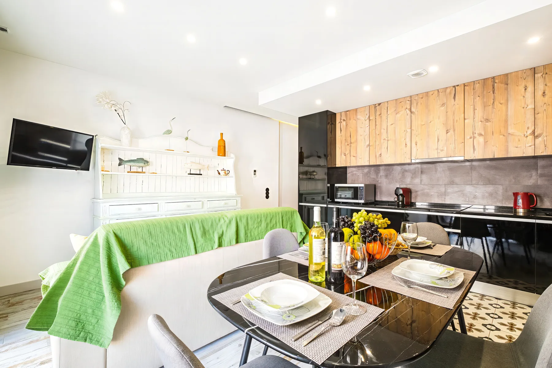 An open-plan living and dining area with a green-covered sofa beside a kitchen.