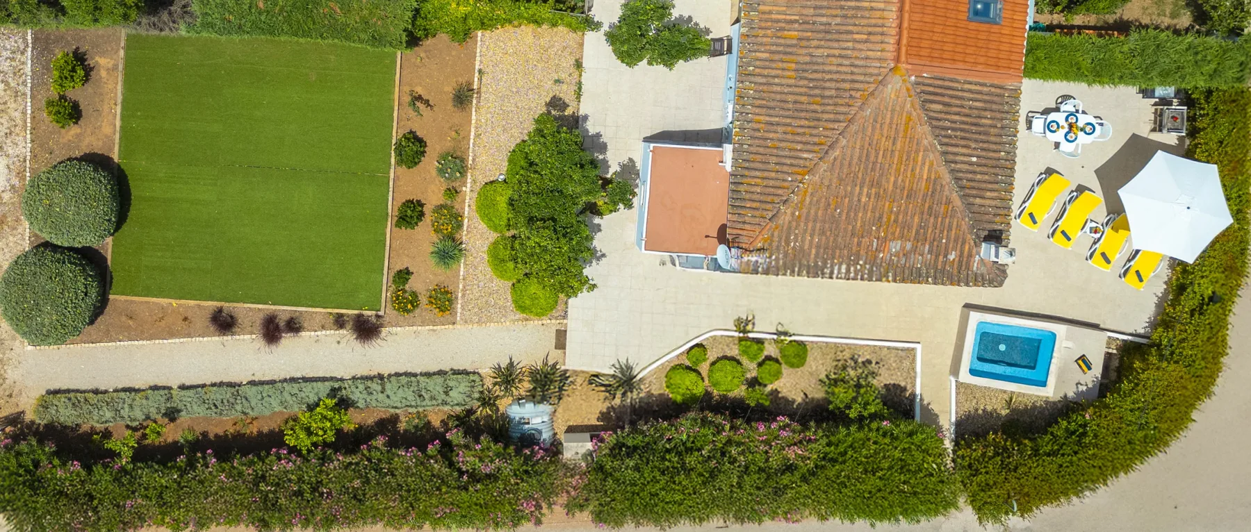 An aerial view of a landscaped property with a lawn, swimming pool, and outdoor seating area.