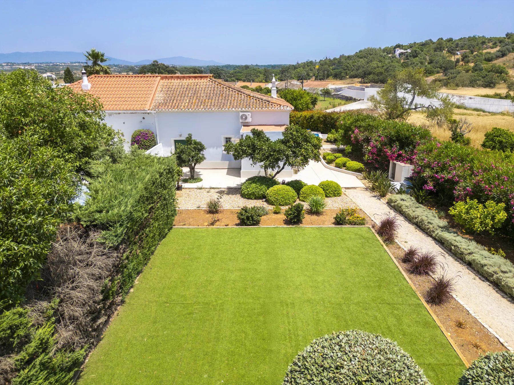 A landscaped garden with a broad lawn, shrubs, and a tiled-roof building.