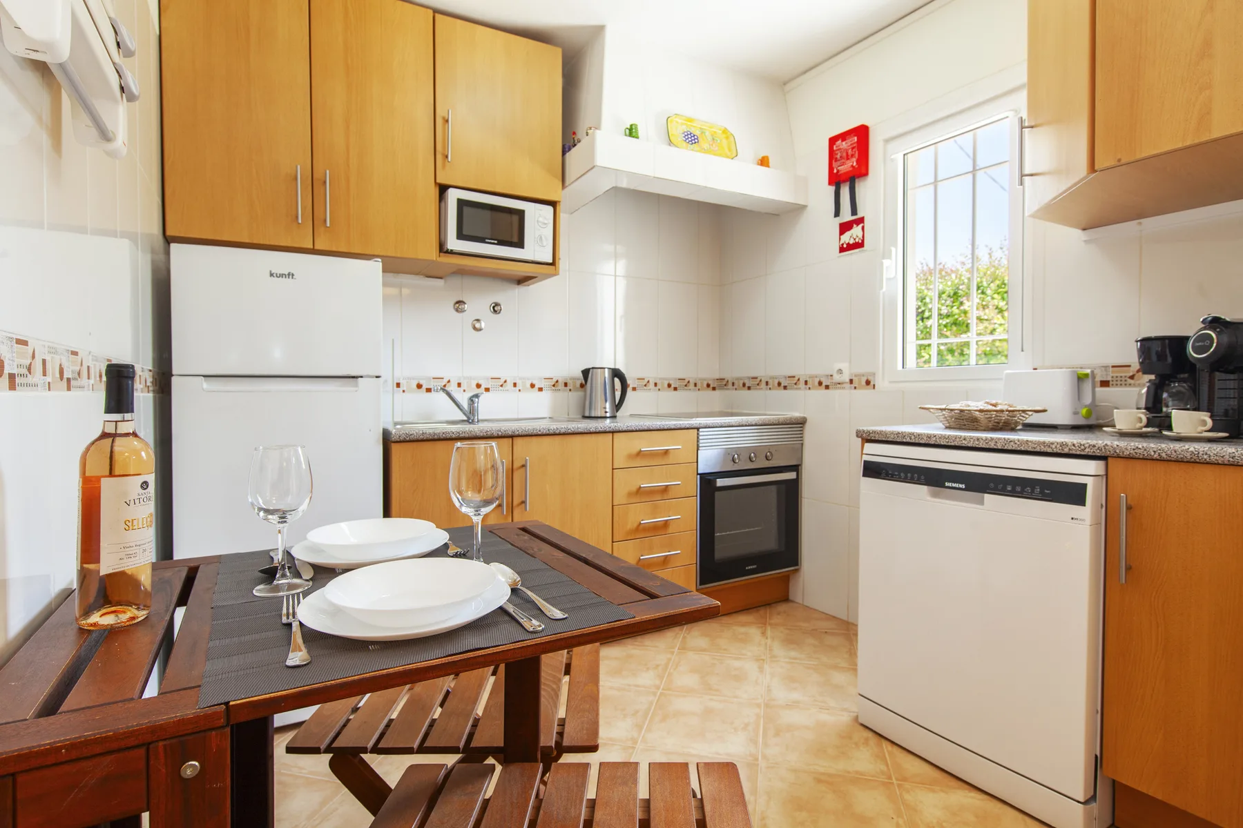 A bright kitchen with wooden cabinets, a dining table, and a window.