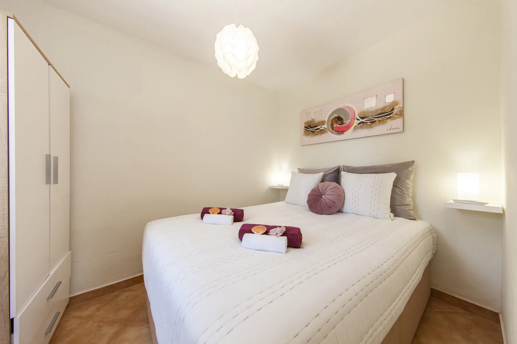 A bedroom with a neatly made bed and a wardrobe.