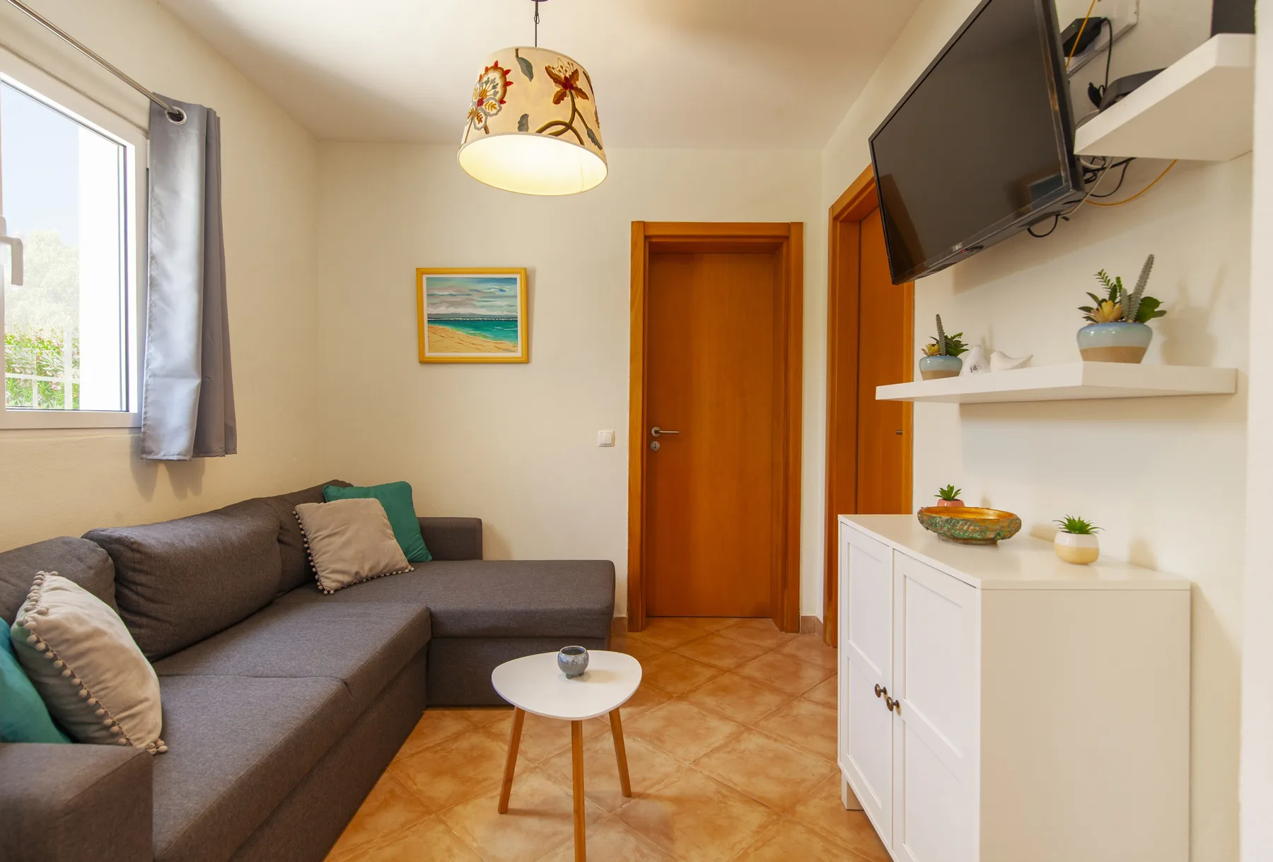 A living room with a sectional seating area, a television, and a wooden door.