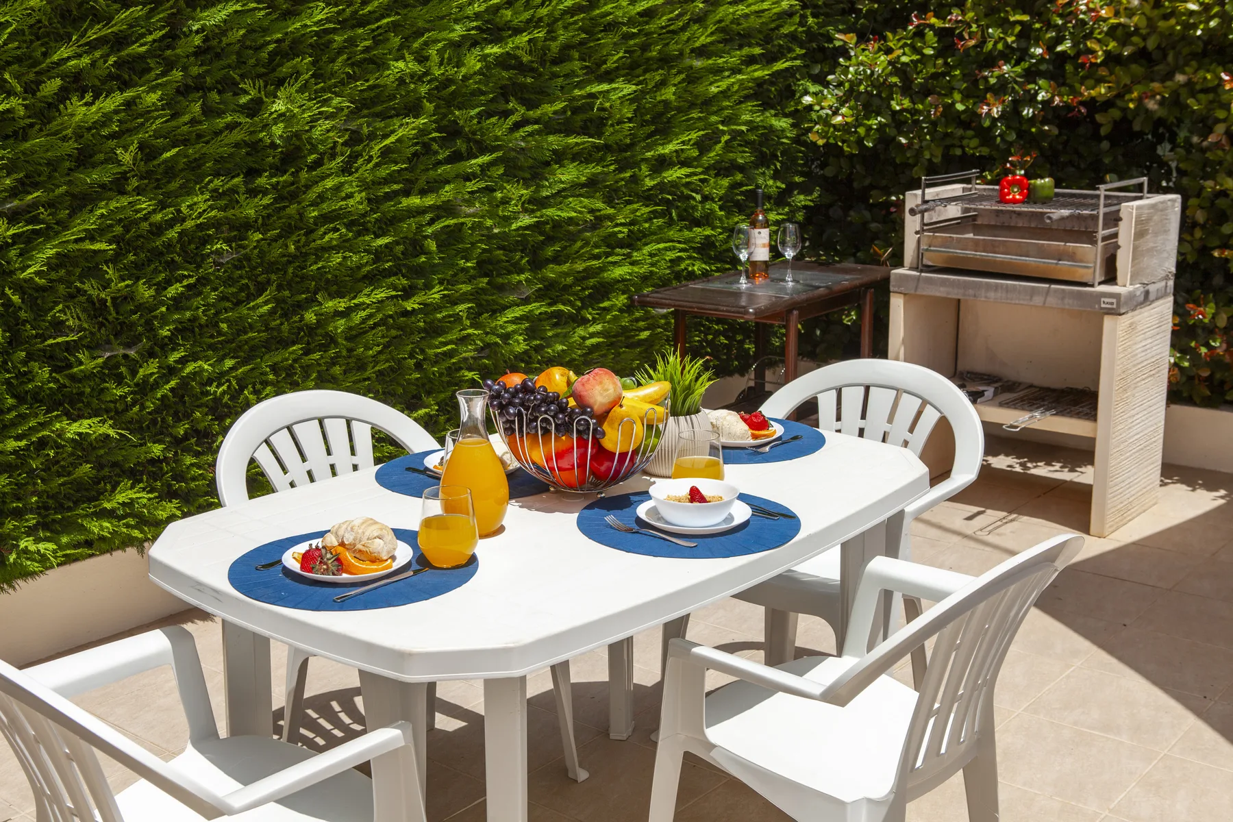 An outdoor dining area with a set table beside a built-in grill.