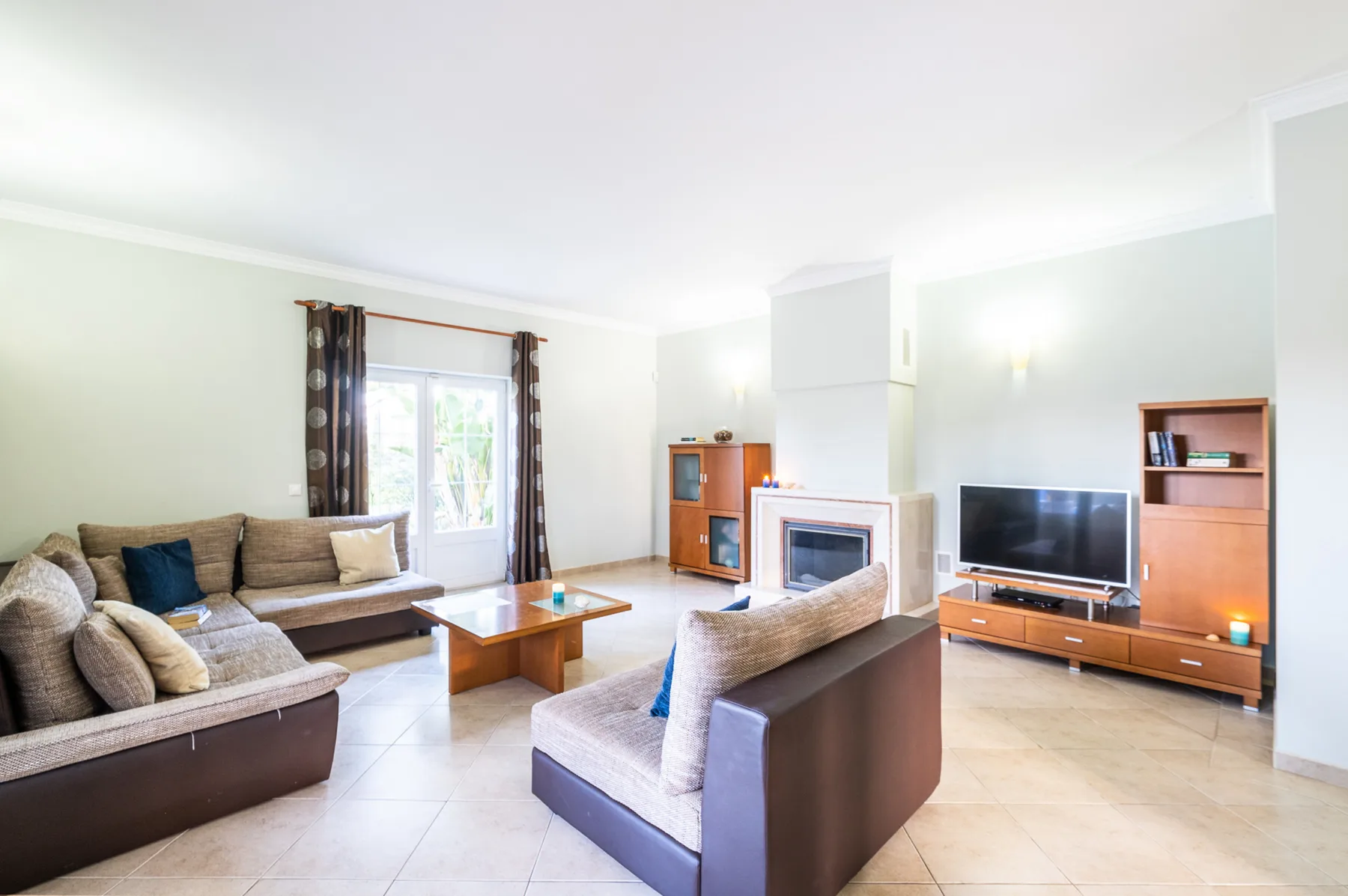 Una sala de estar luminosa con asientos alrededor de una mesa de centro y un televisor.
