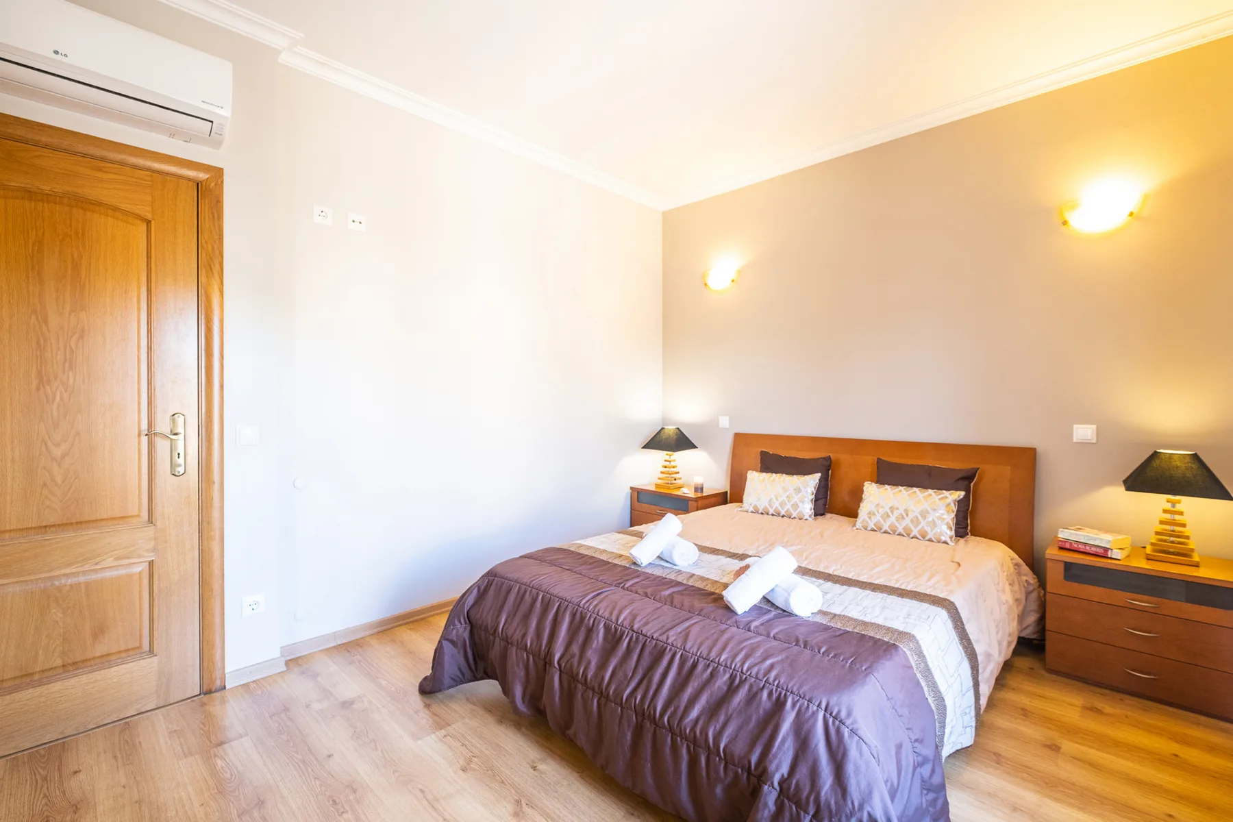 Un dormitorio con una cama doble, mesitas de noche y una puerta de madera.