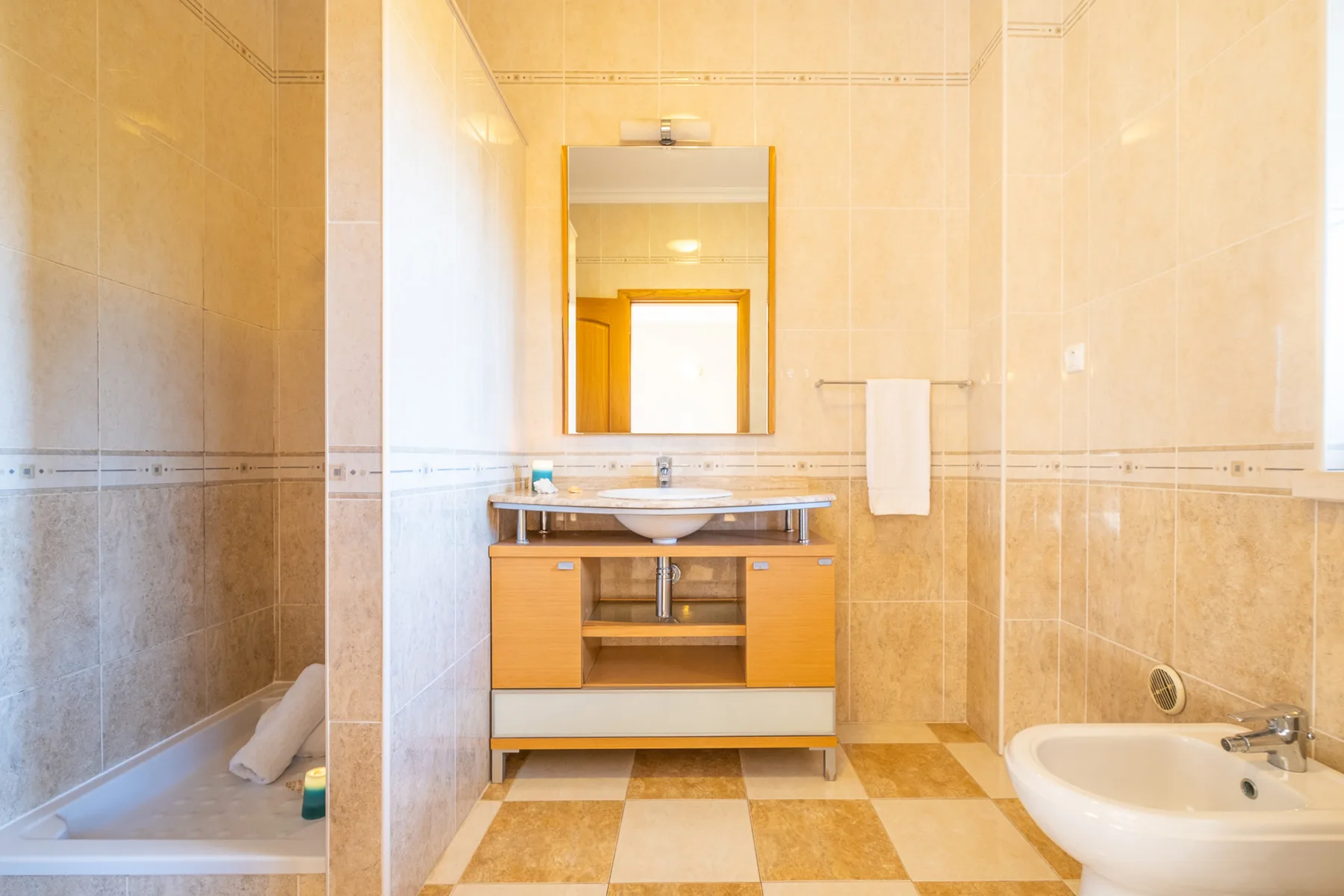 Un baño alicatado con lavabo, espejo, ducha y bañera.