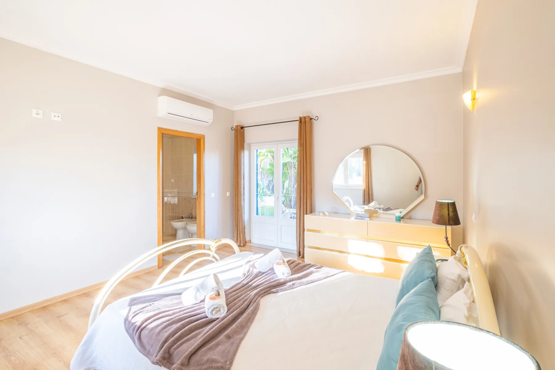 Un dormitorio luminoso con una cama doble, una cómoda y una puerta de cristal.