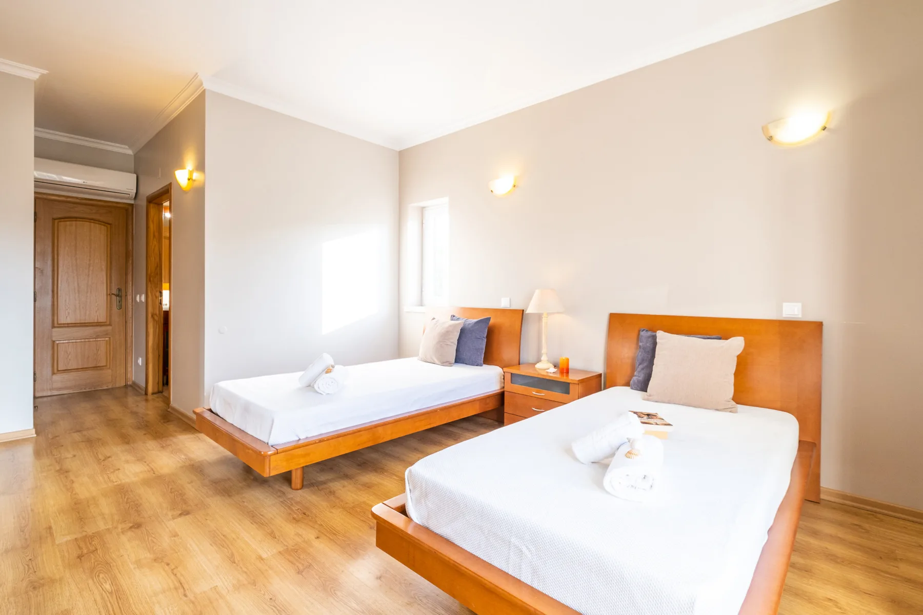 Un dormitorio luminoso con dos camas y una mesita de noche.