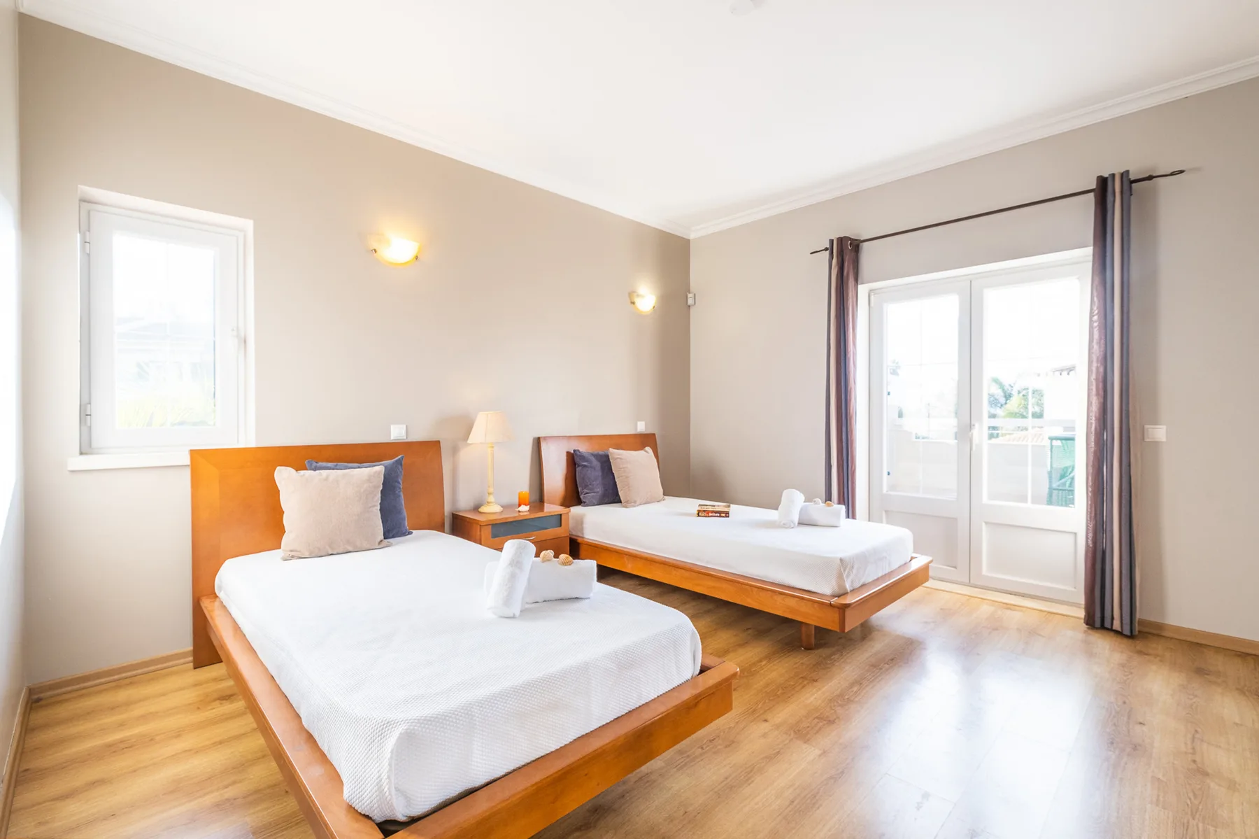 Un dormitorio luminoso con dos camas y grandes ventanas con vistas al exterior.