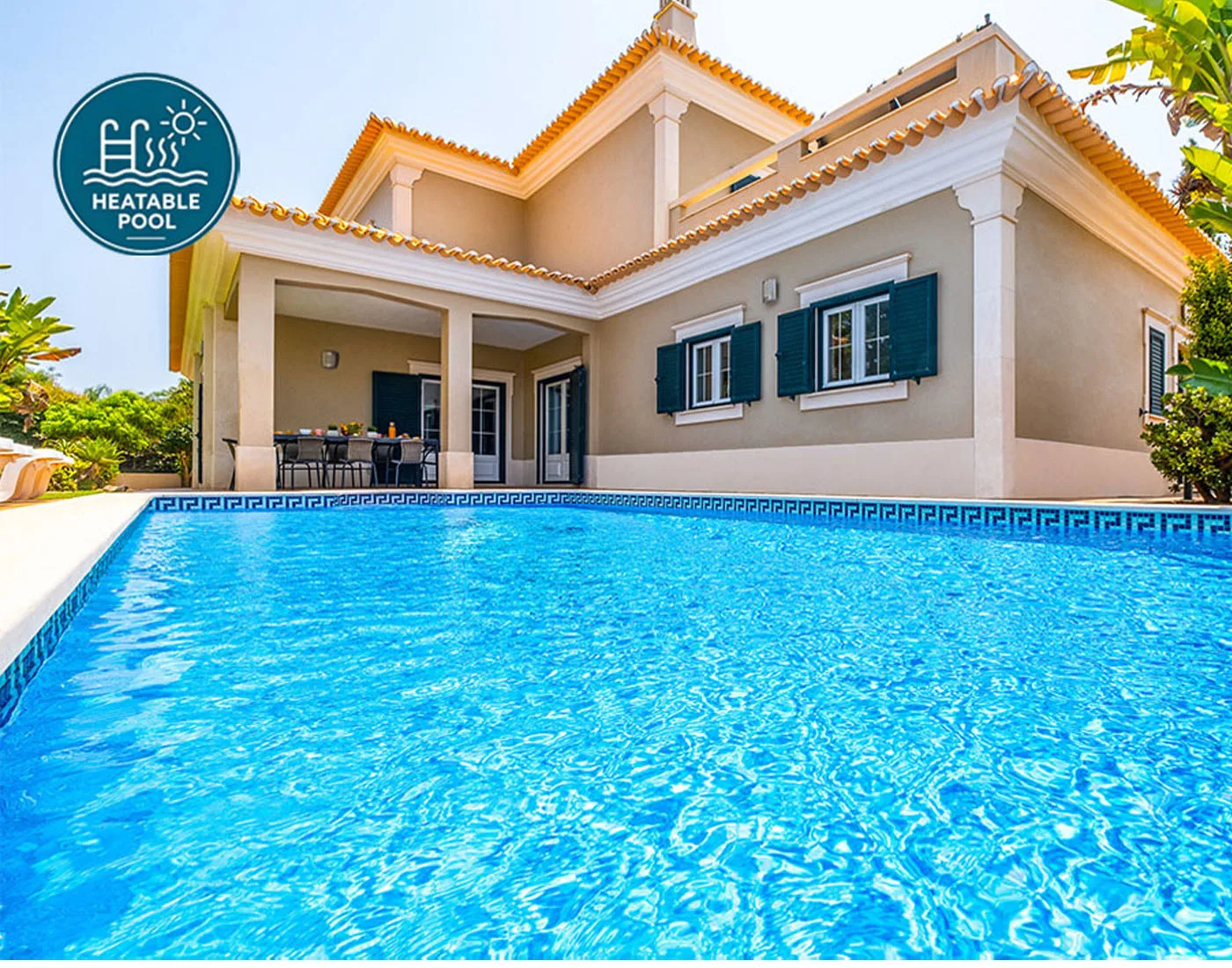 Una piscina frente a una casa grande con un patio cubierto.