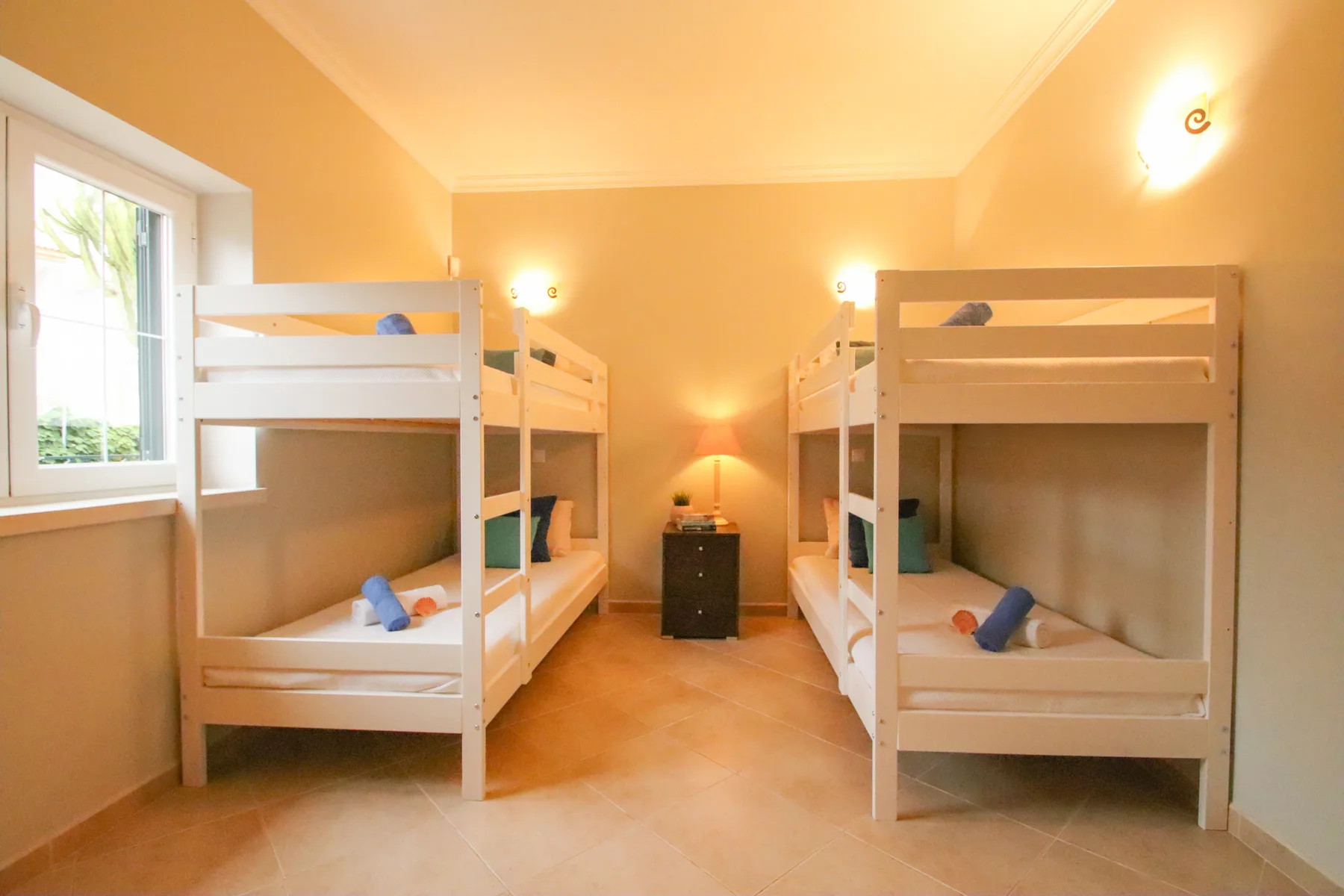 Un dormitorio en tonos cálidos con literas y una pequeña mesita de noche.
