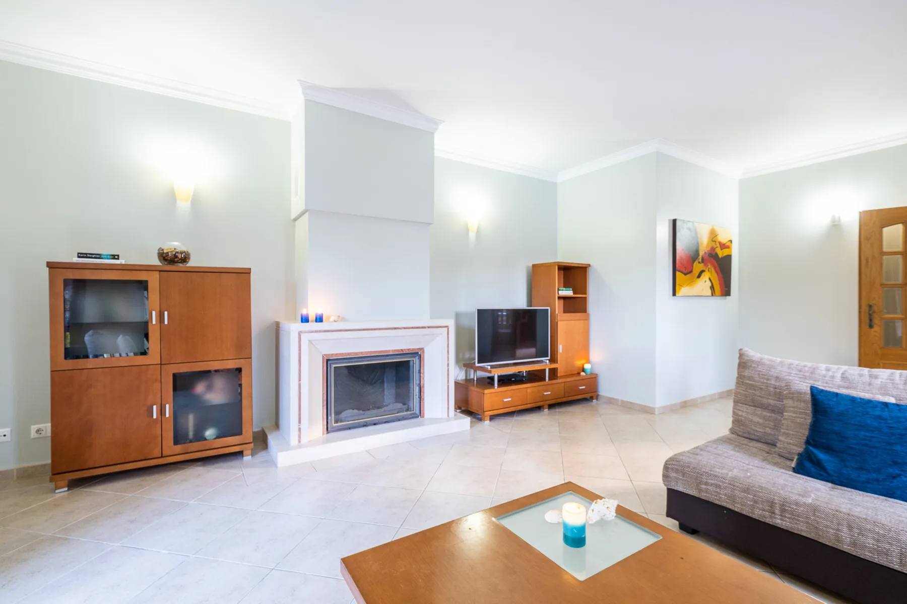 Una sala luminosa con chimenea, televisor y asientos.
