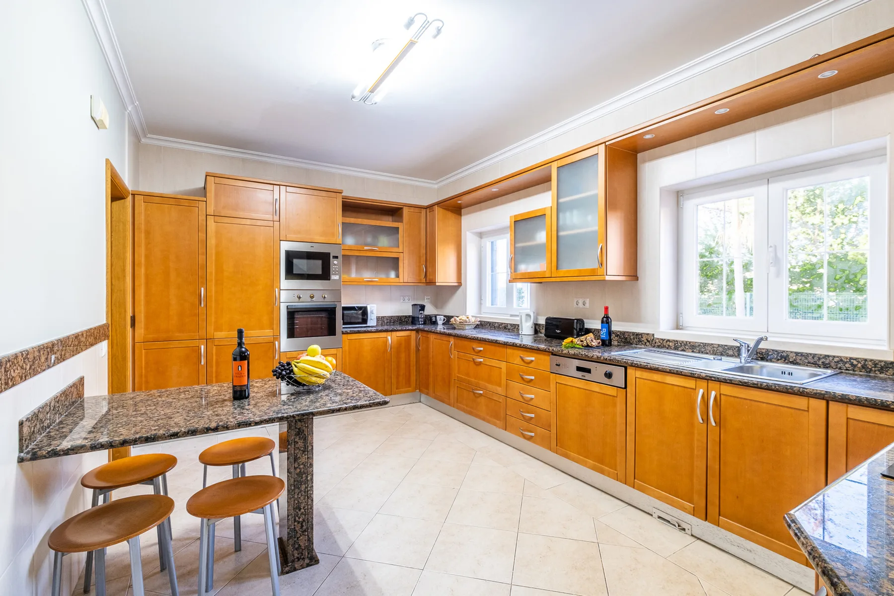 Una cocina luminosa con armarios de madera, encimeras oscuras y una isla central.