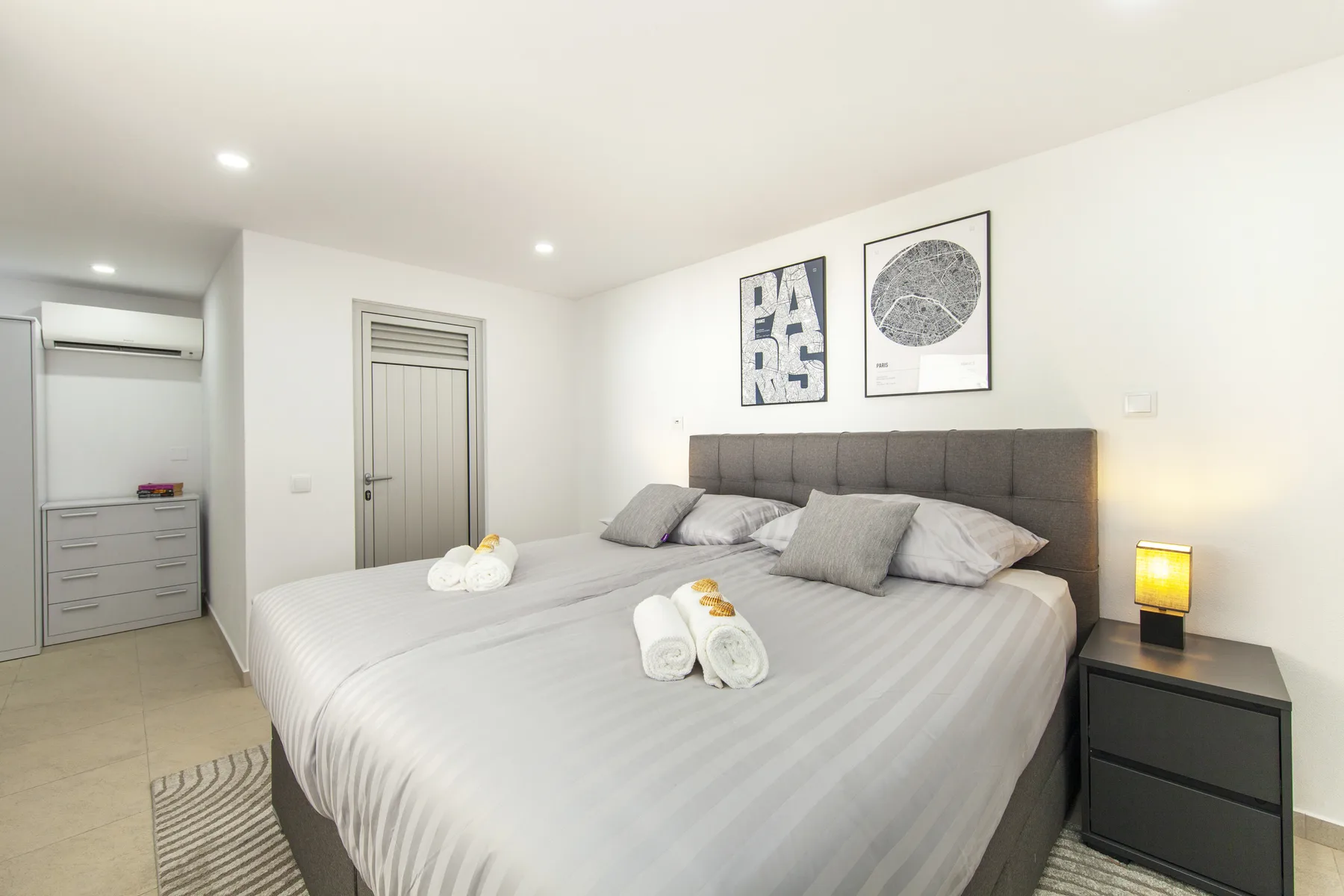 Un dormitorio luminoso con una cama grande y cuadros enmarcados sobre el cabecero.