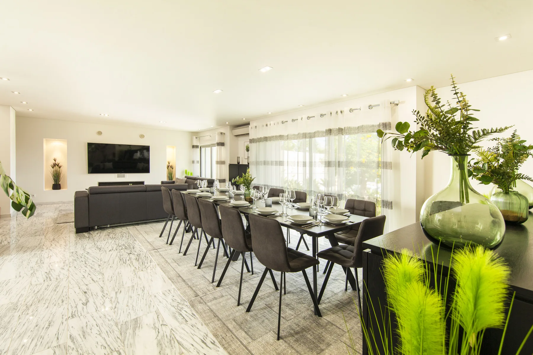 Luminoso espacio abierto de sala y comedor, con una mesa larga junto a la zona de estar.