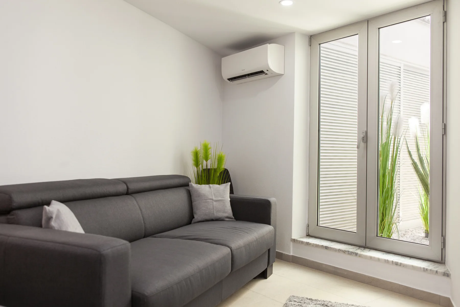 Una sala luminosa con asientos grises junto a puertas altas de vidrio.