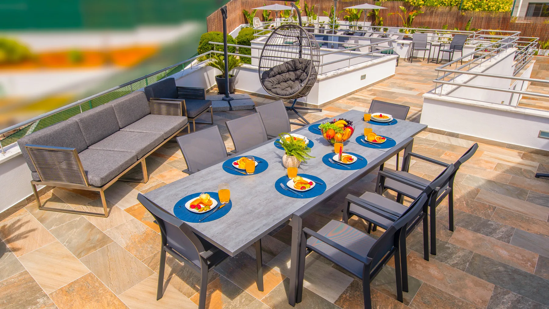 Una terraza exterior con una mesa preparada con platos coloridos y flores.