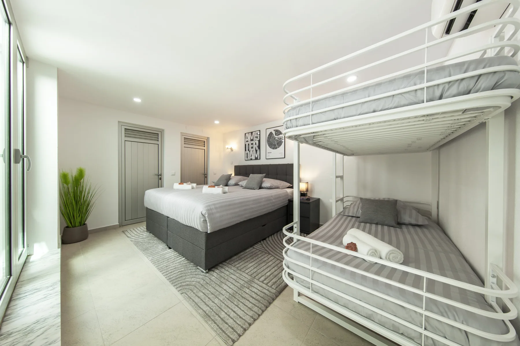 Un dormitorio con una cama grande y una litera metálica blanca.