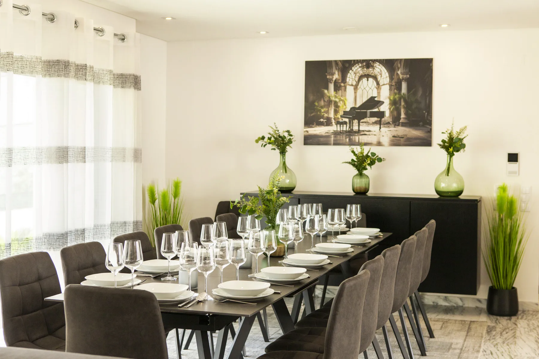 Un comedor con una mesa larga preparada con platos y cristalería.