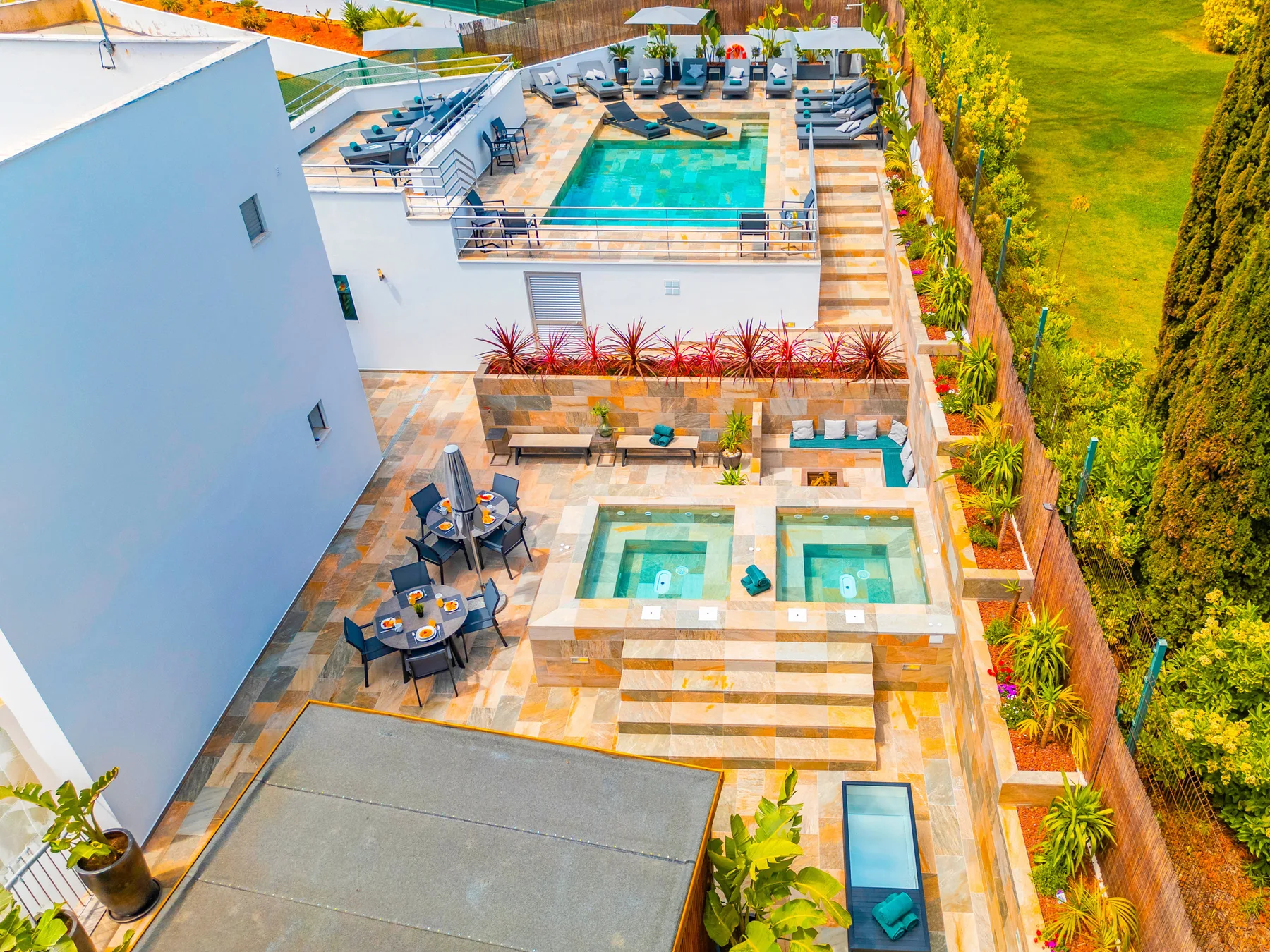 Una terraza exterior con piscina, asientos de descanso y bordes ajardinados.