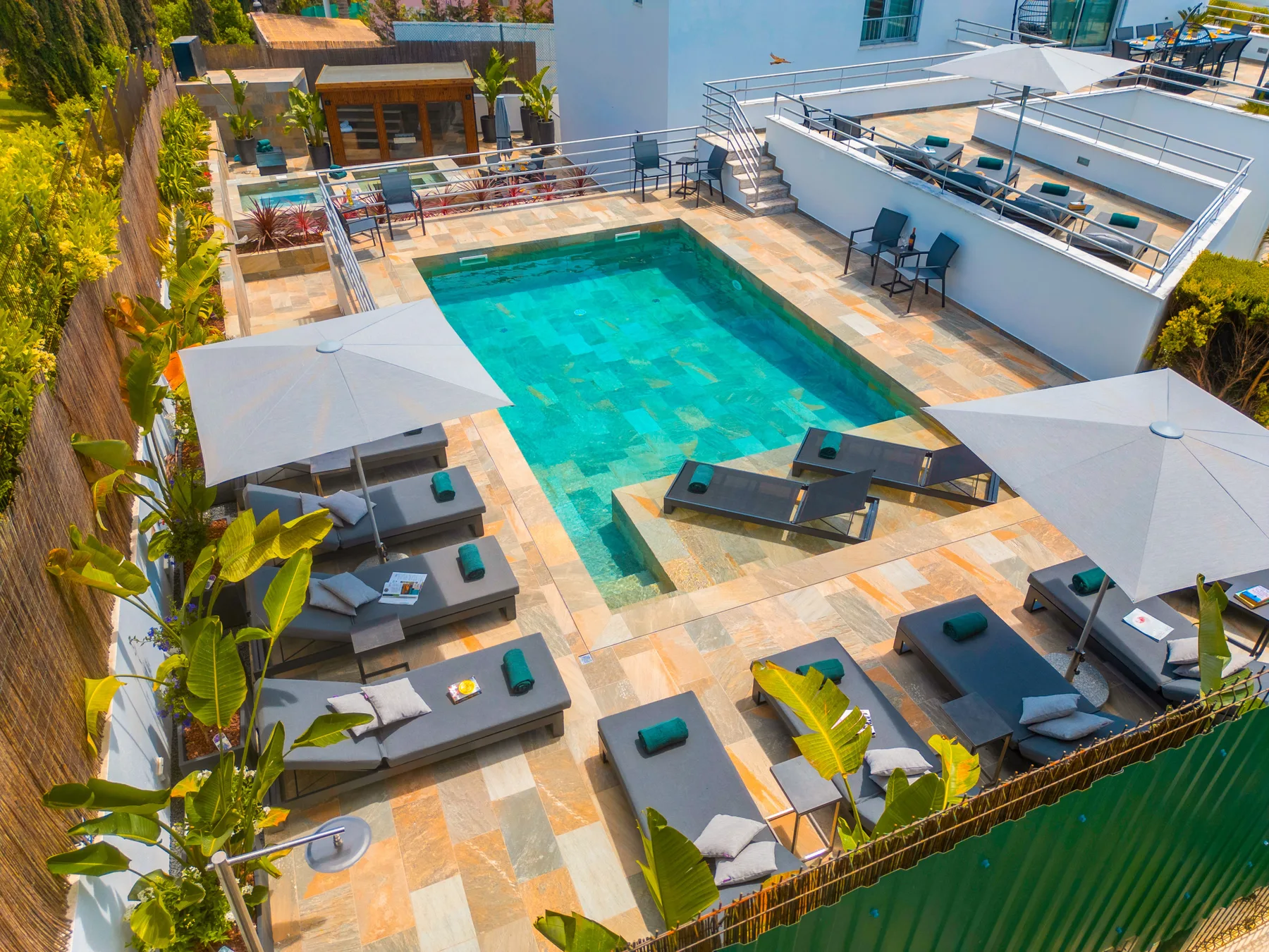 Una piscina al aire libre está rodeada de asientos y sombrillas de patio.
