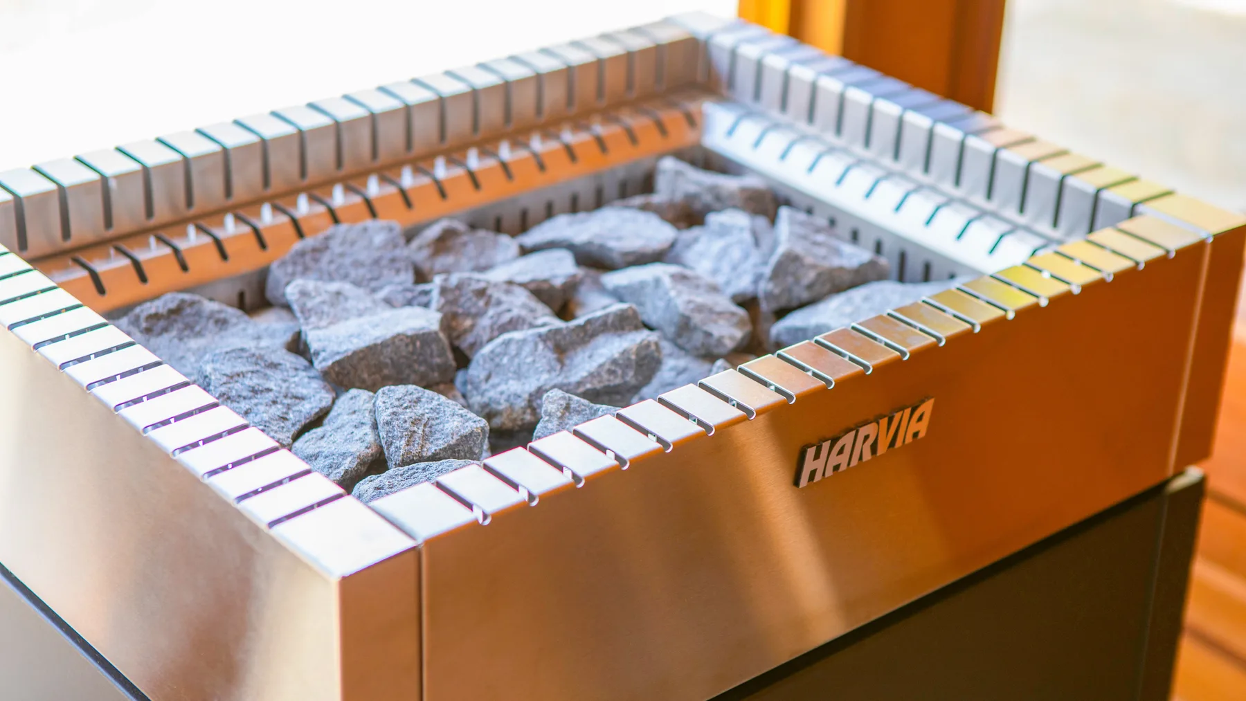 Un calentador de sauna lleno de piedras está rodeado por un borde de azulejos.