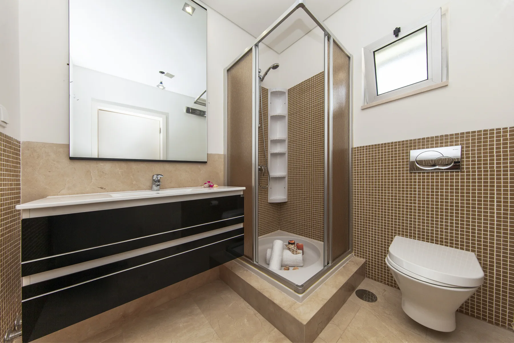 Un baño moderno con ducha de vidrio, lavabo y sanitario.
