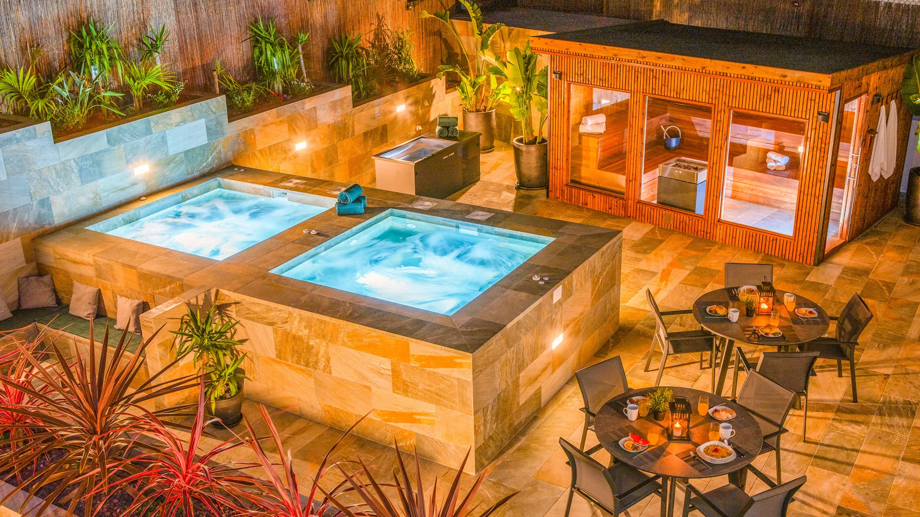 Una zona de spa al aire libre con dos piscinas de hidromasaje y asientos cercanos.