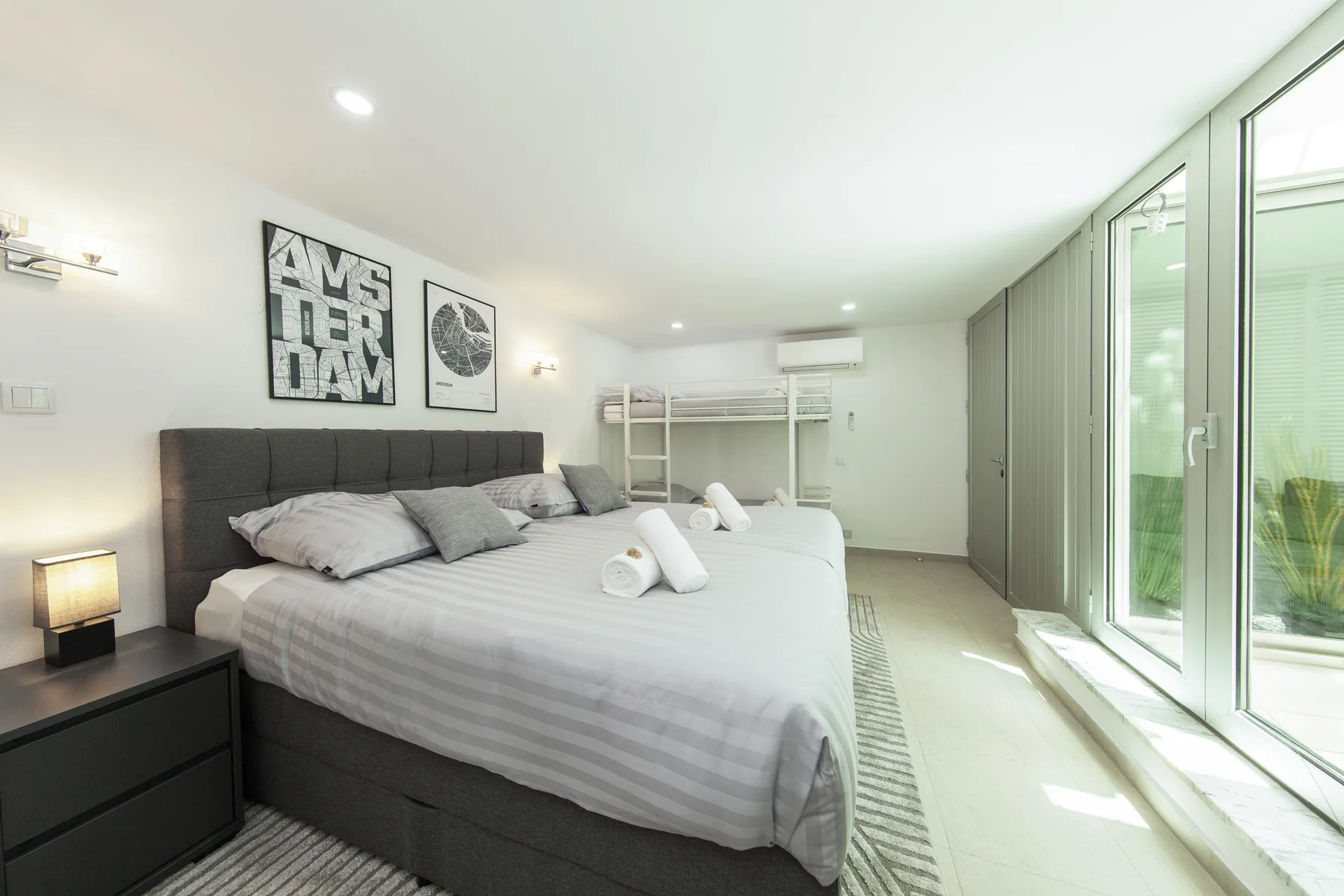Un dormitorio luminoso con una cama grande y puertas de vidrio de piso a techo.